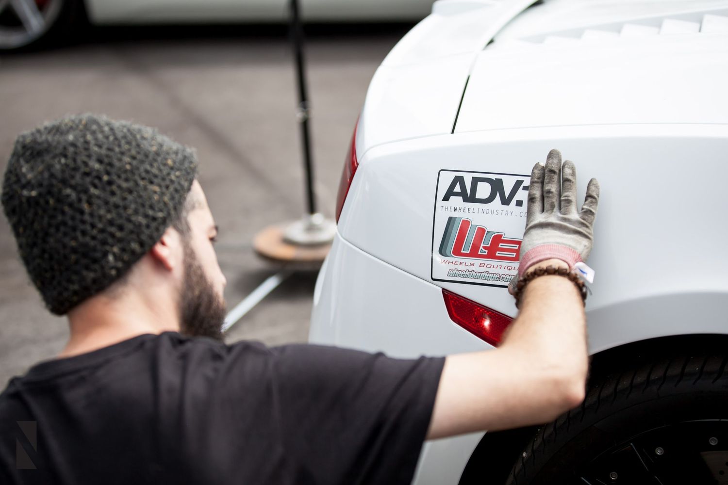 A technician installing an ADVAN performance decal on a white vehicle.
