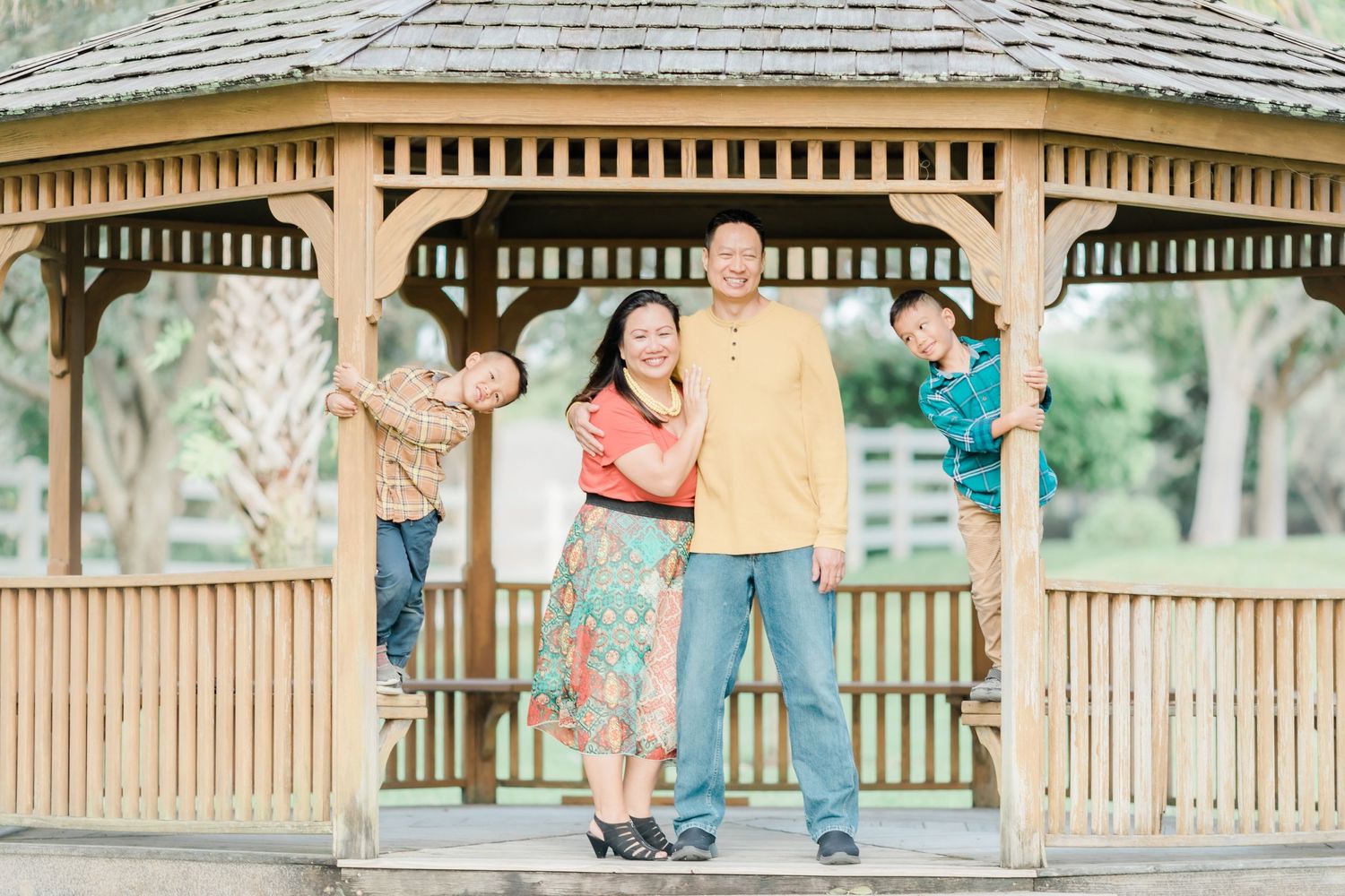 A family strikes fun poses together inside a wooden gazebo.