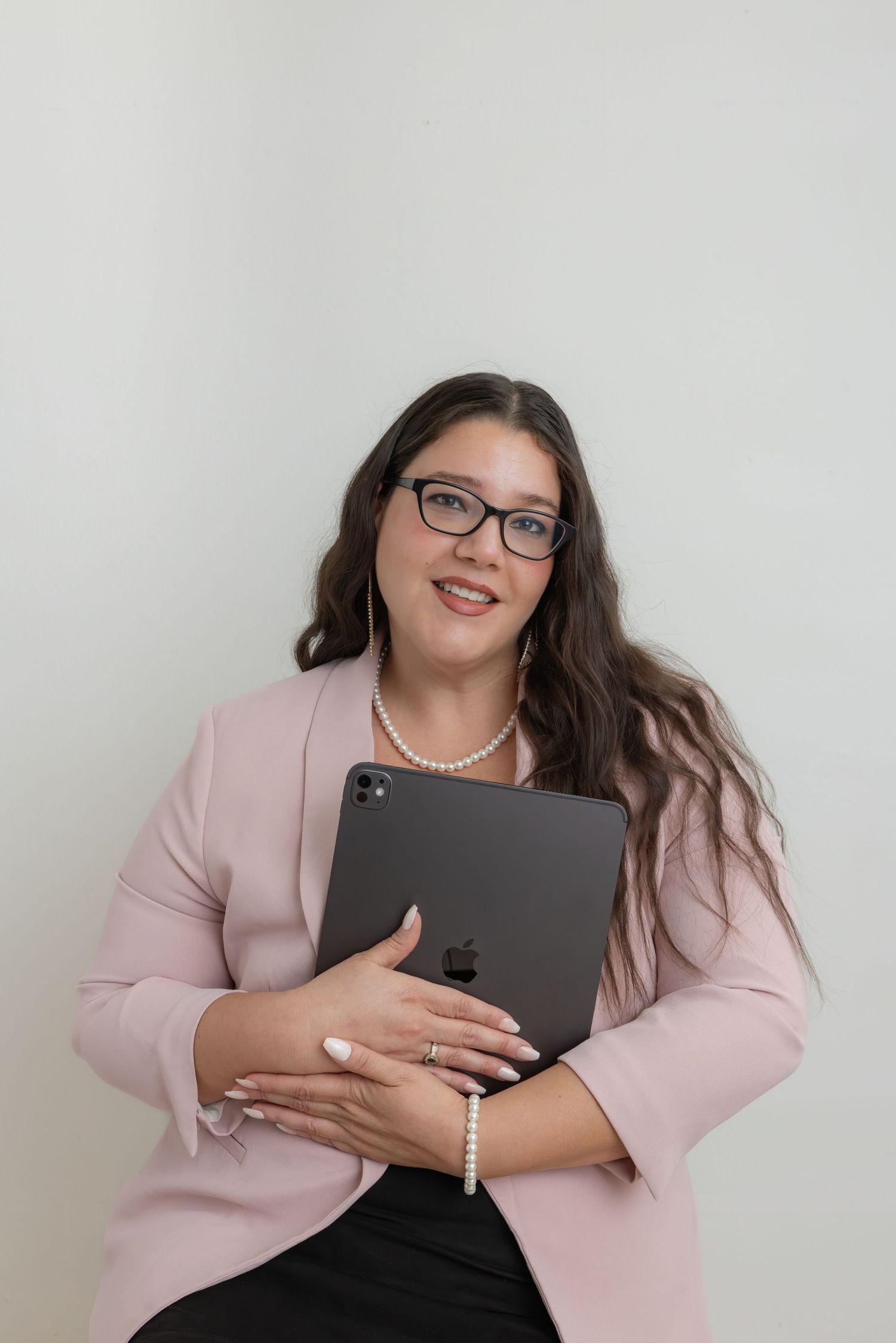 Professional wearing light pink blazer holds iPad or tablet while showing different expressive poses against white background.
