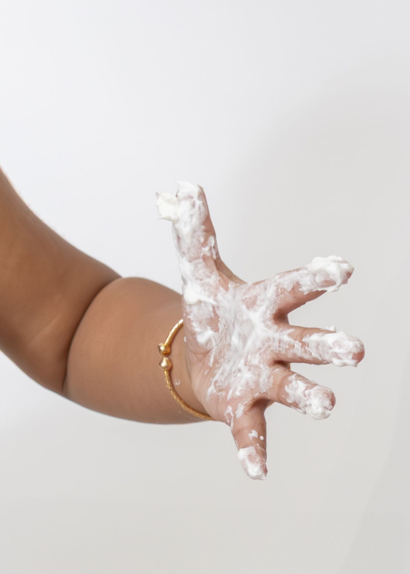 A hand holding white playdough or clay being molded in a progression series of images against a light background.