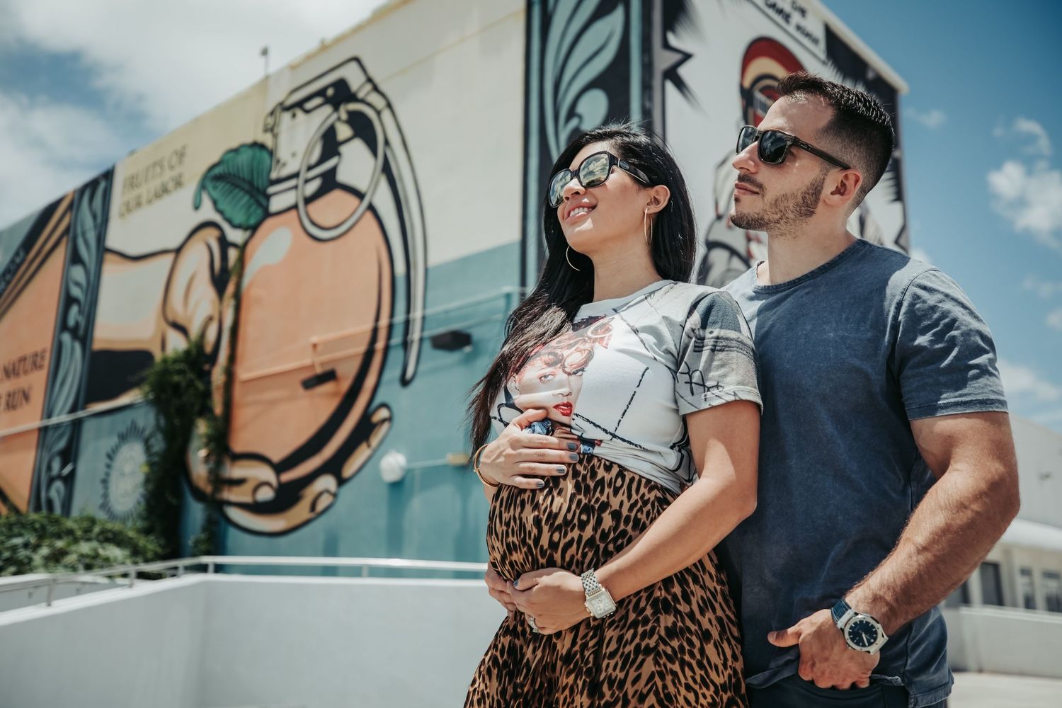 A couple poses together near a retro vehicle while wearing casual summer attire.