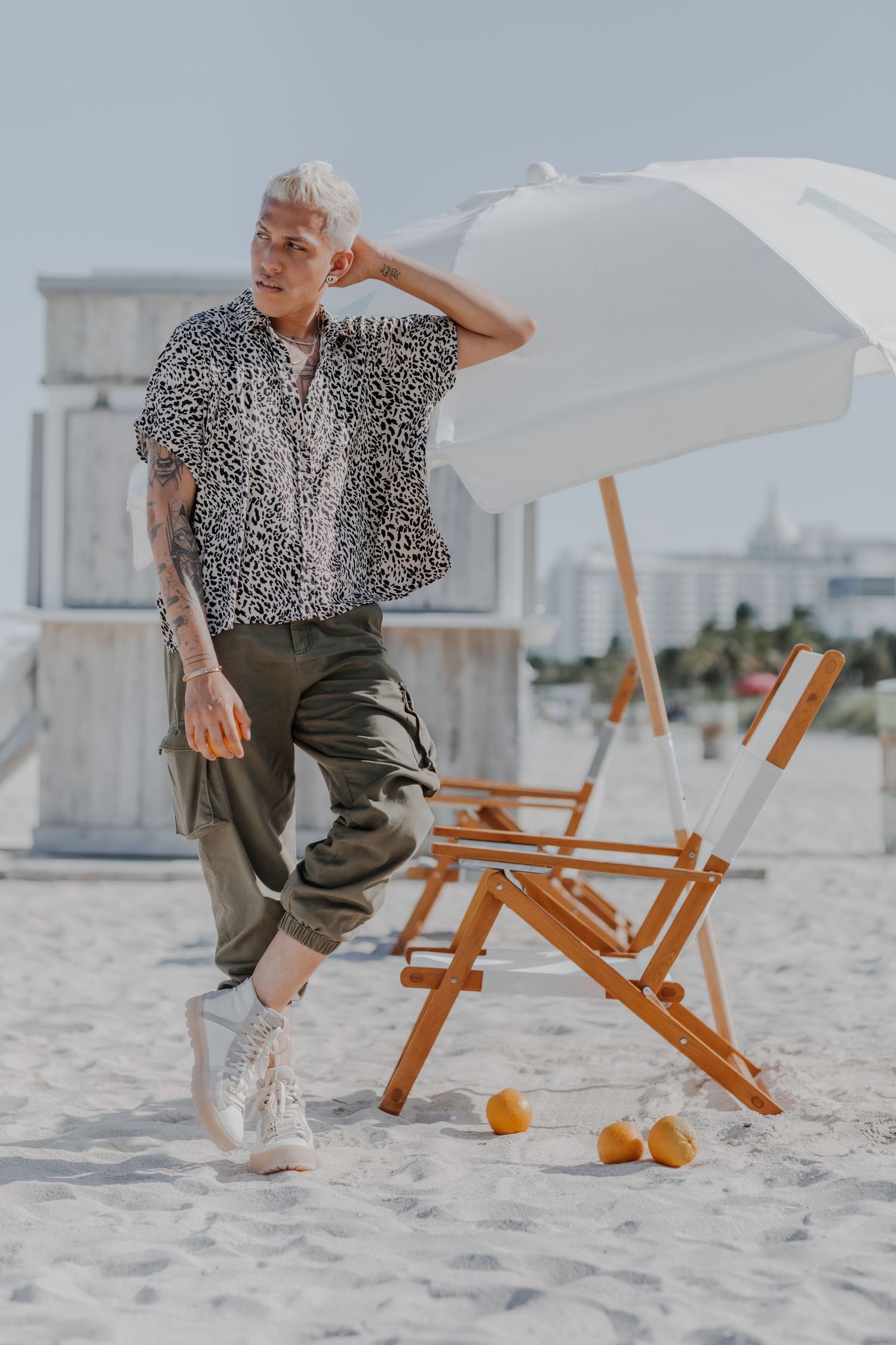 Casual summer fashion shoot on beach with wooden chair and citrus fruits as props.