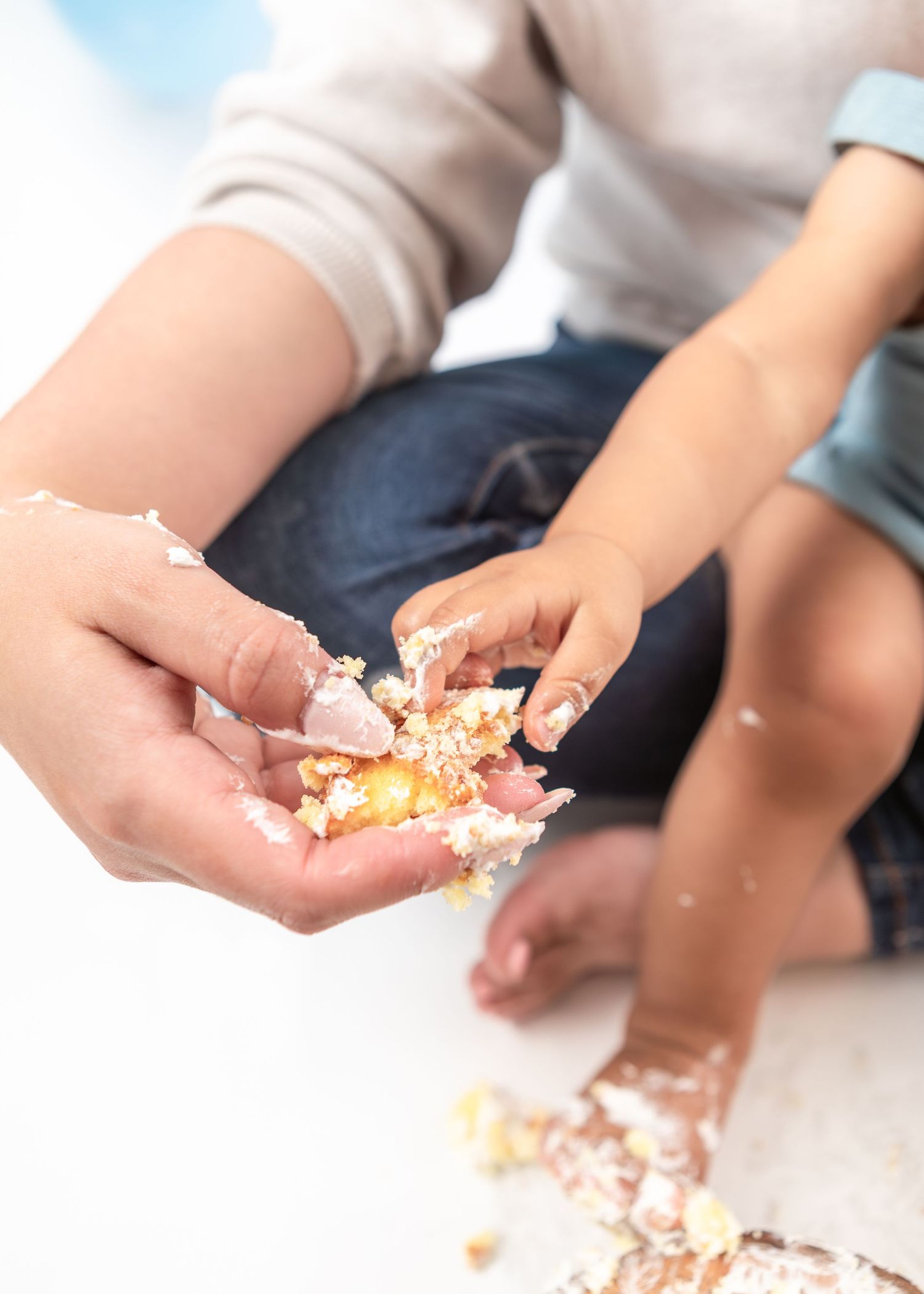 Hands breaking apart cake during celebratory cake smash session.
