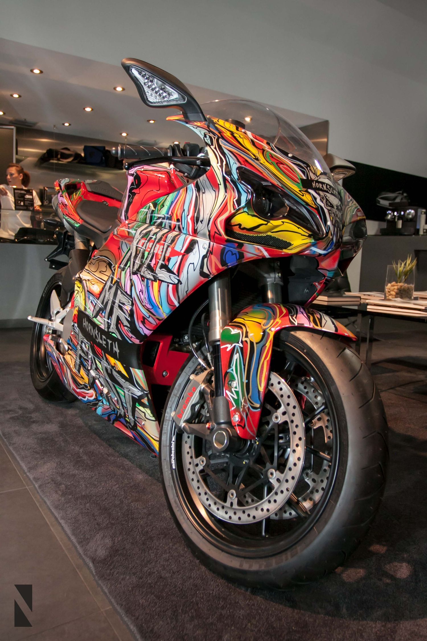 Custom painted sport motorcycle with vibrant graffiti-style artwork displayed in a showroom on dark carpet floor.