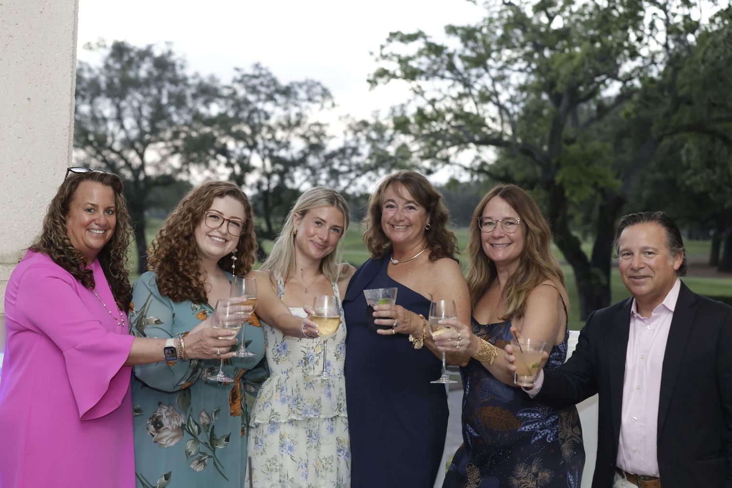 A group of friends enjoy drinks together at an outdoor event during dusk.
