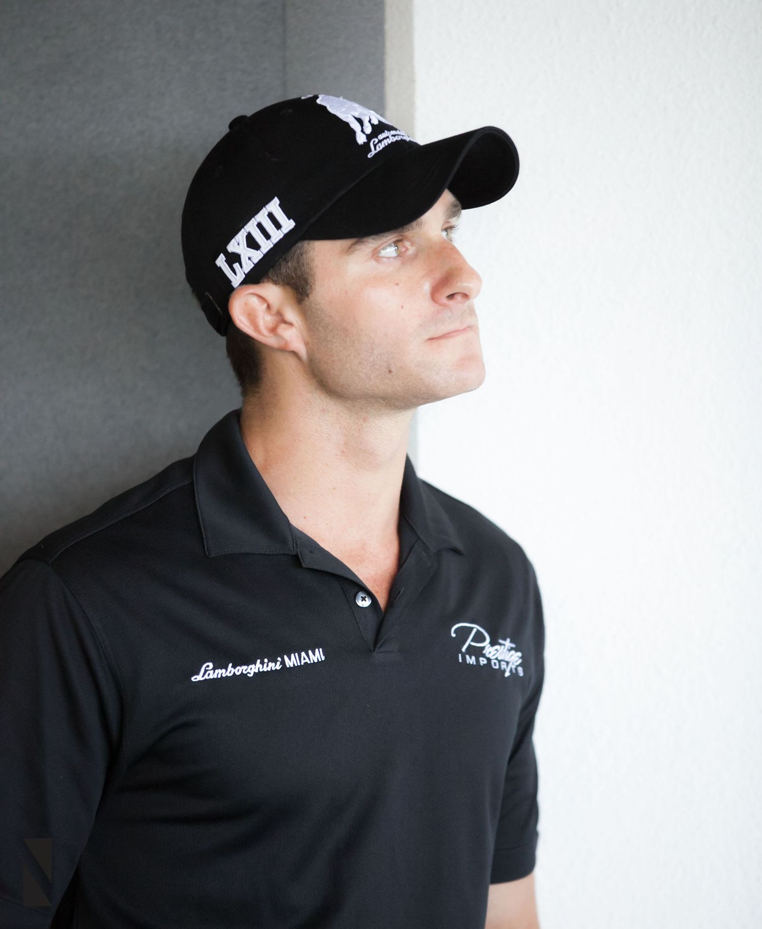 Person wearing a black baseball cap and polo shirt in front of a gray background.