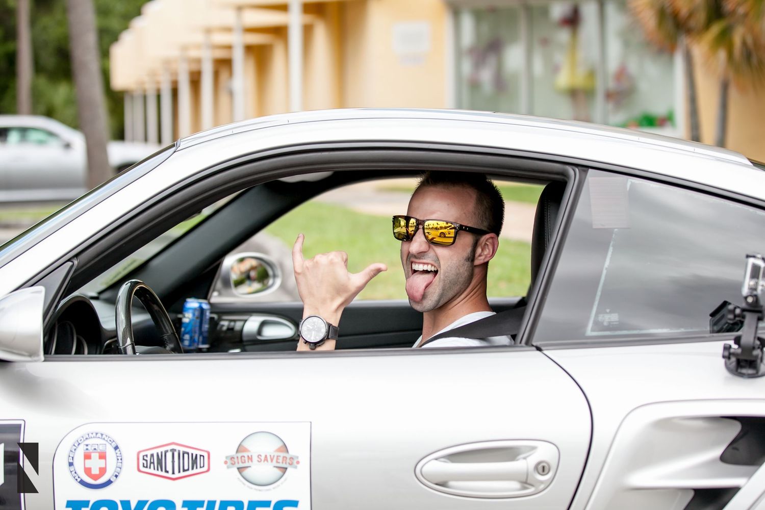 Driver in car with sponsors stickers showing excitement through window.