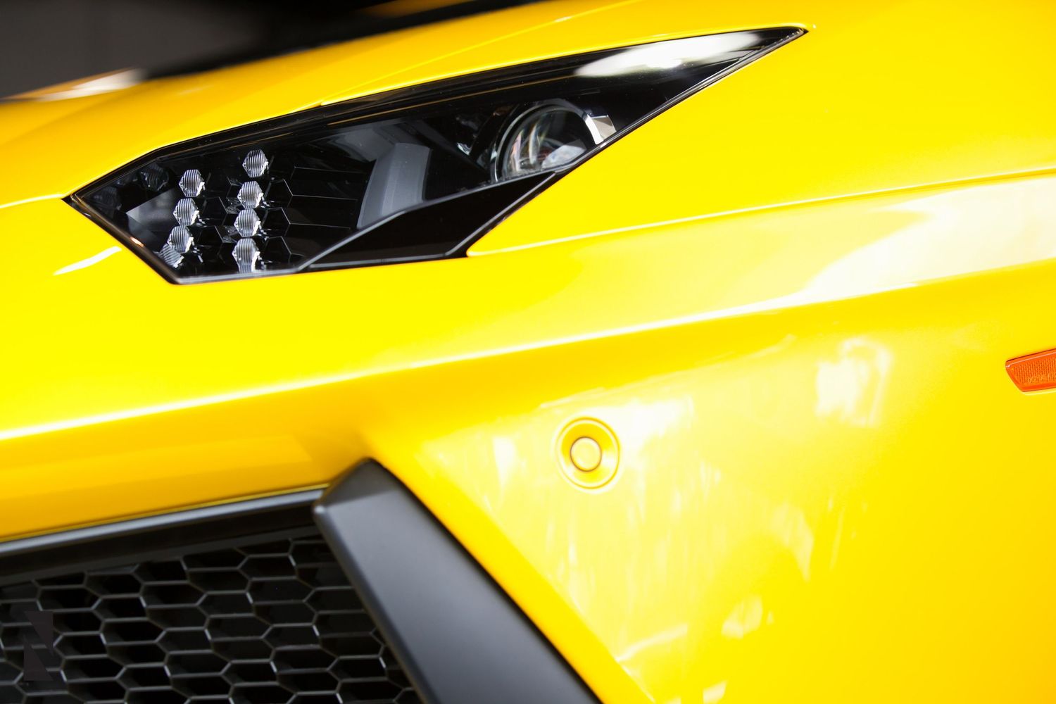 Close-up detail of a yellow Lamborghini's LED headlight design against the sleek bodywork.