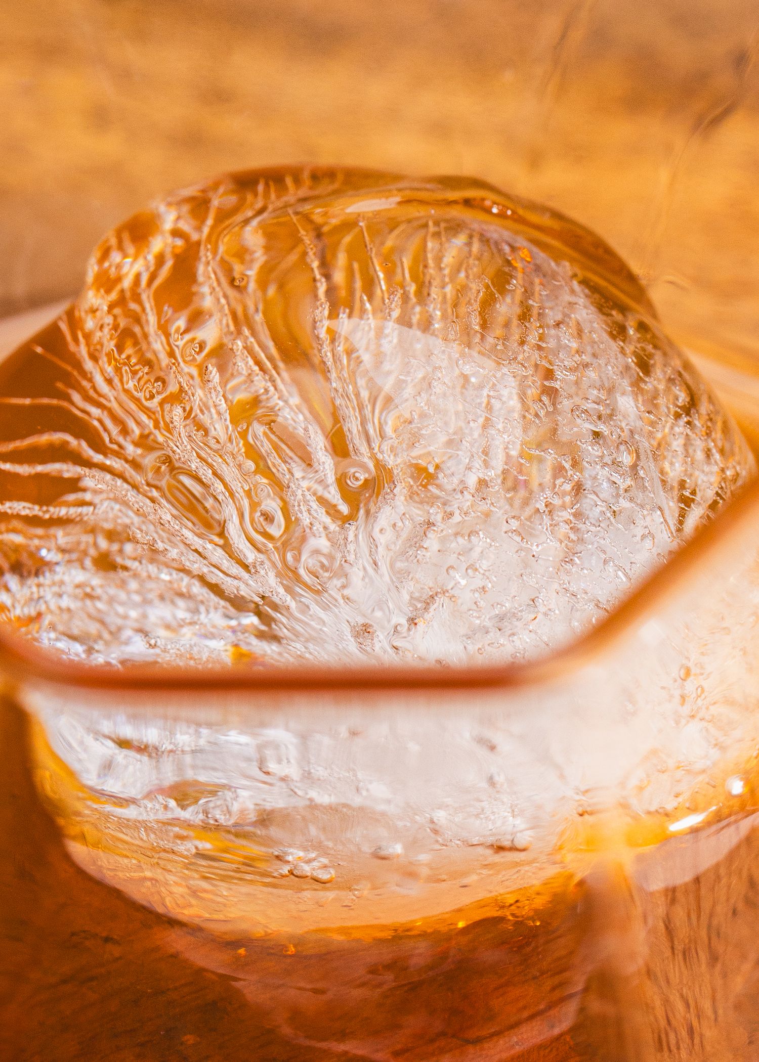 A creamy white and golden cream puff pastry with a glossy, flakey surface texture on a wooden surface.