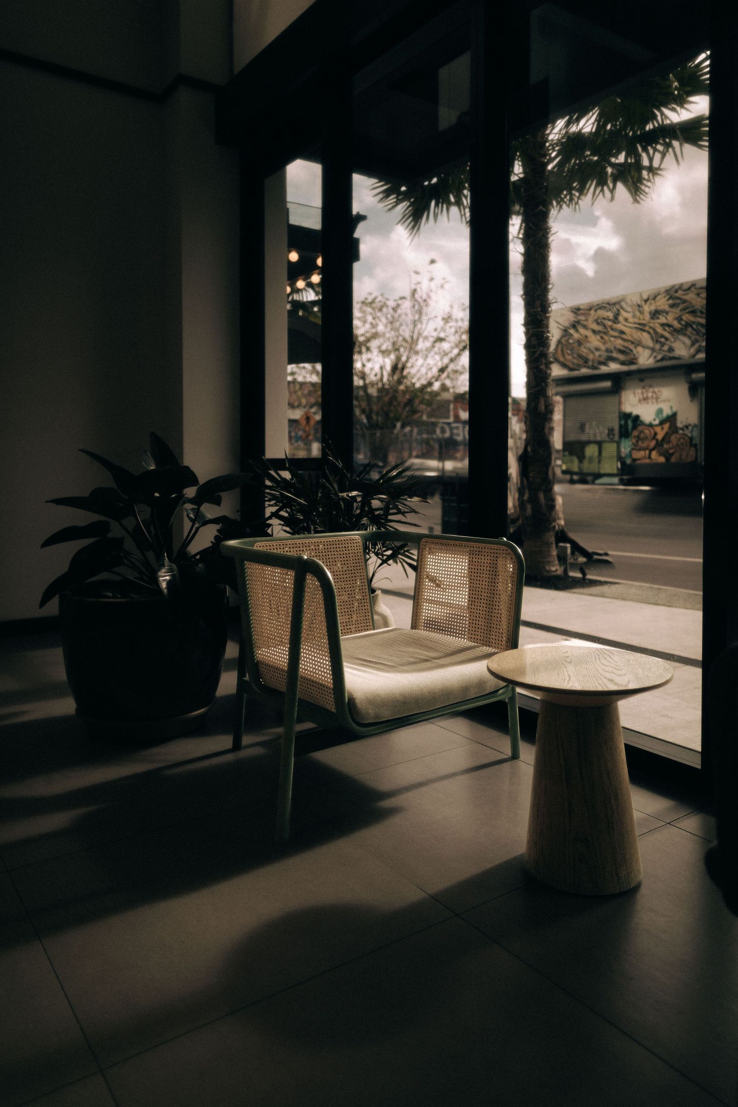 Modern patio setting with wicker chair and side table in moody lighting.