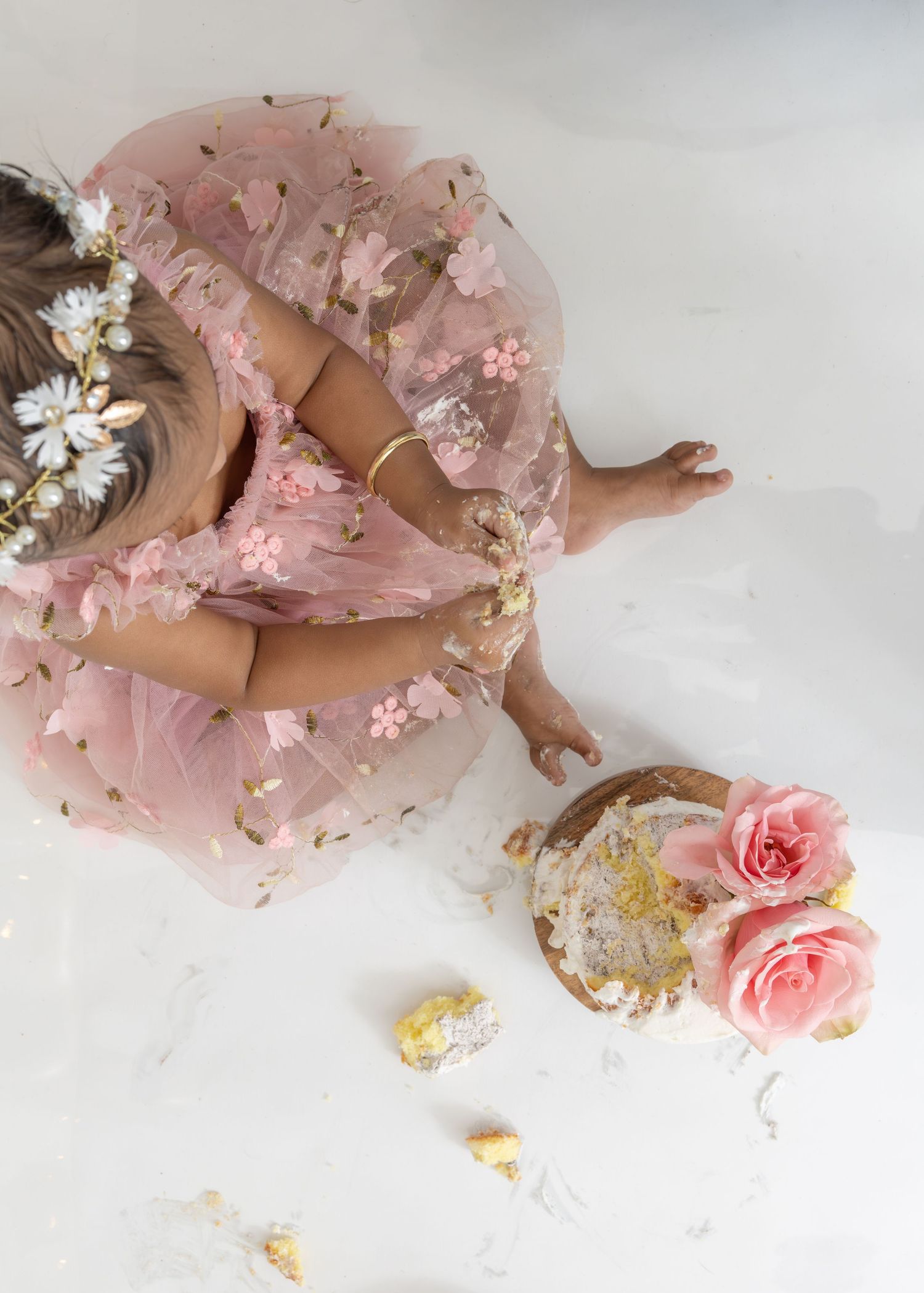 Pink tulle fabric adorned with delicate daisies and roses creates a romantic composition on a white surface.