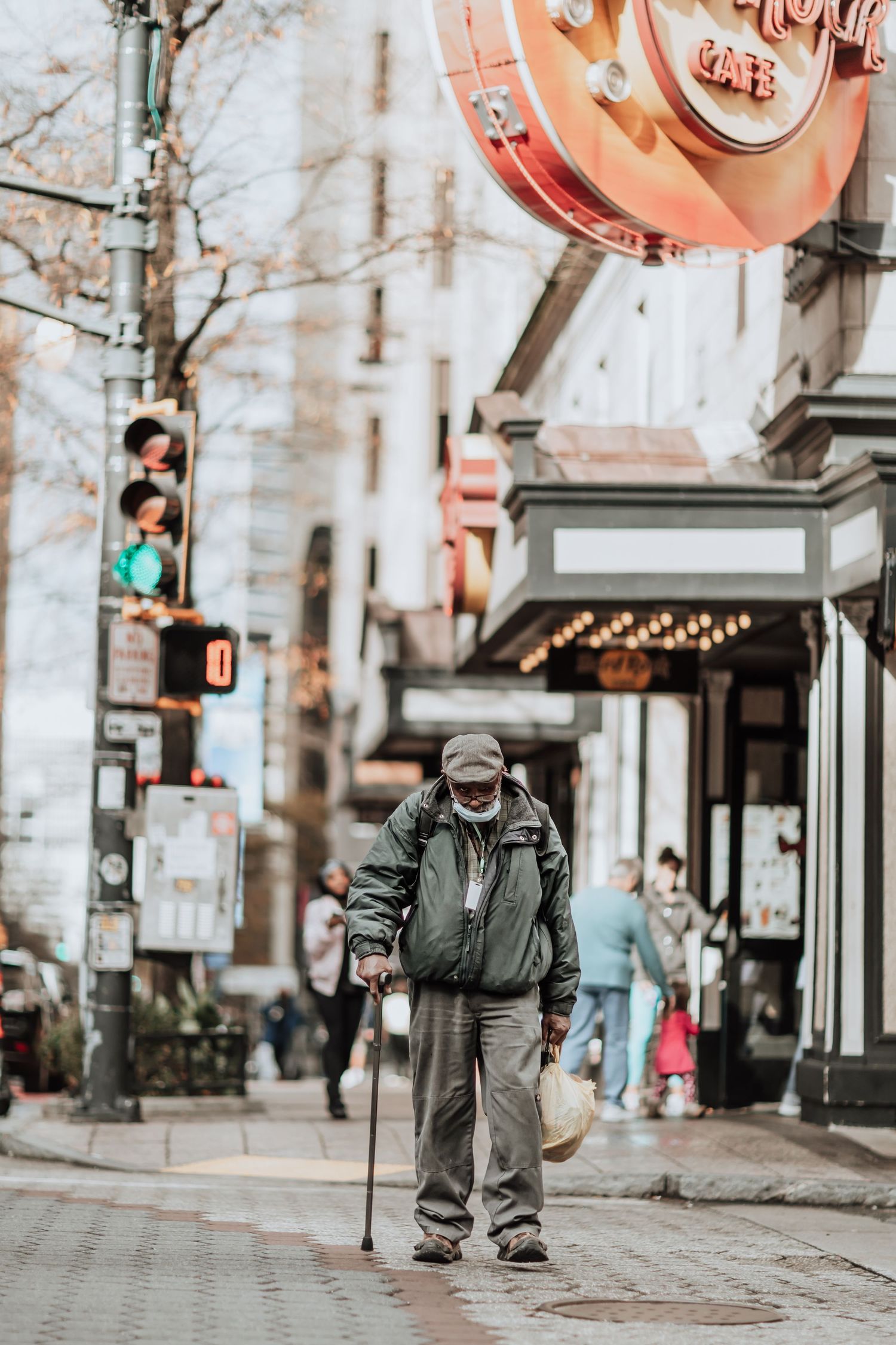 Person walking with cane on city sidewalk under vintage storefront signs.