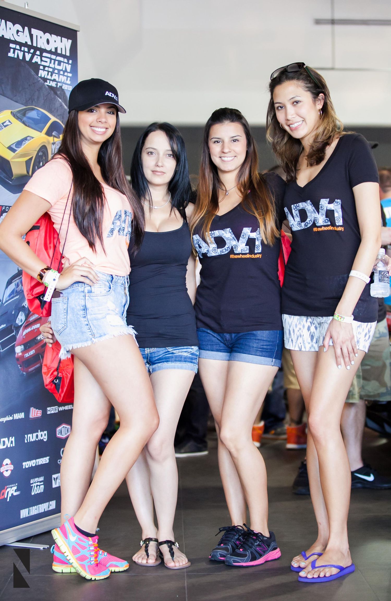 Group of promotional models wearing DY1 branded shirts posing at automotive event.