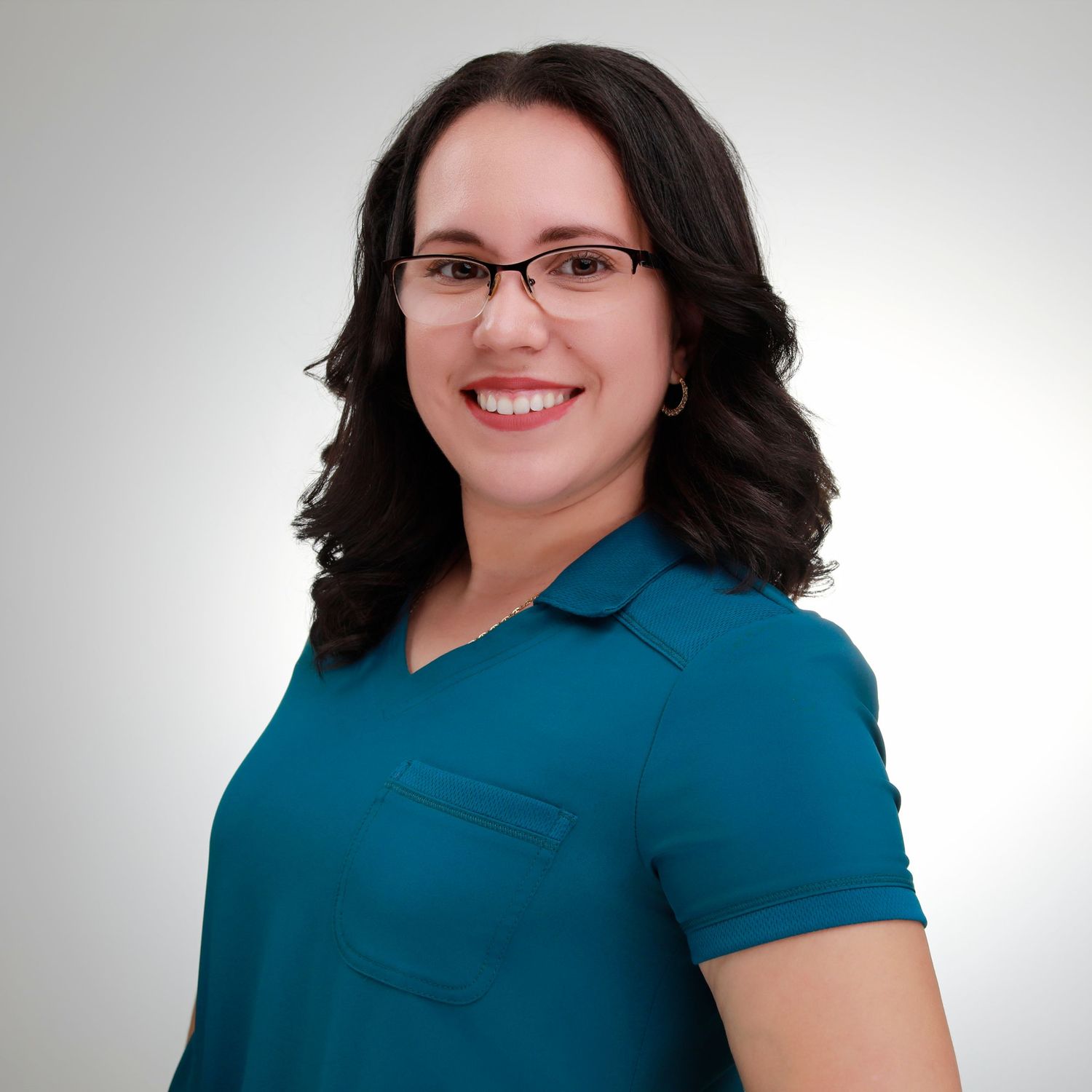 Professional portrait wearing glasses and a teal collared shirt against a light backdrop.