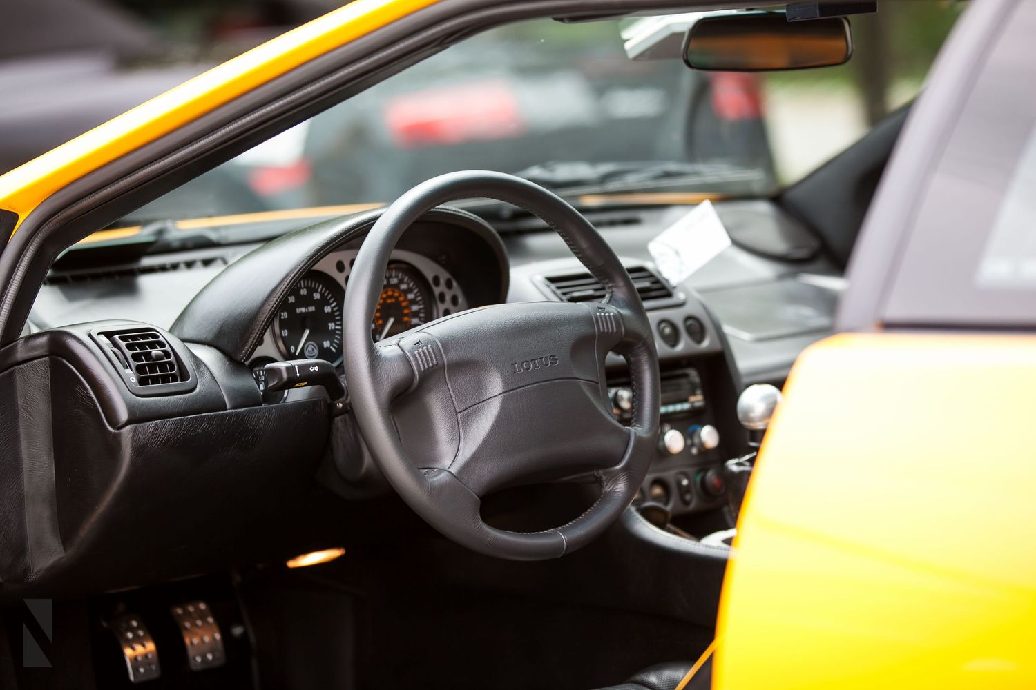 Interior view of a yellow car showing steering wheel and dashboard controls.