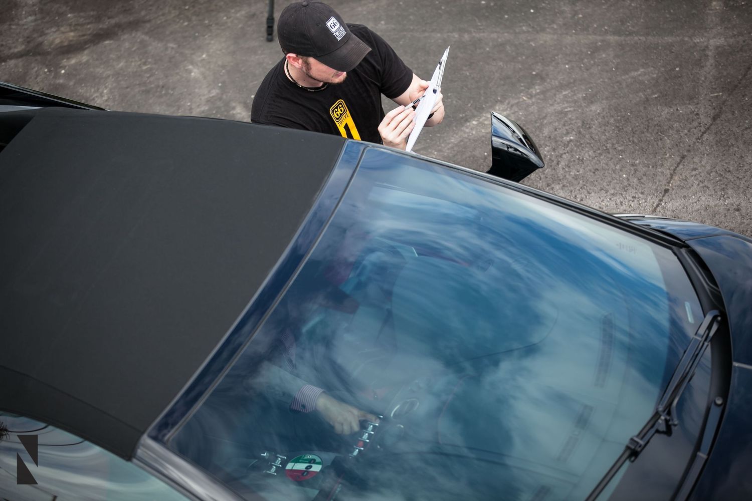 A person applies a protective film or wrap to a car's black roof panel.