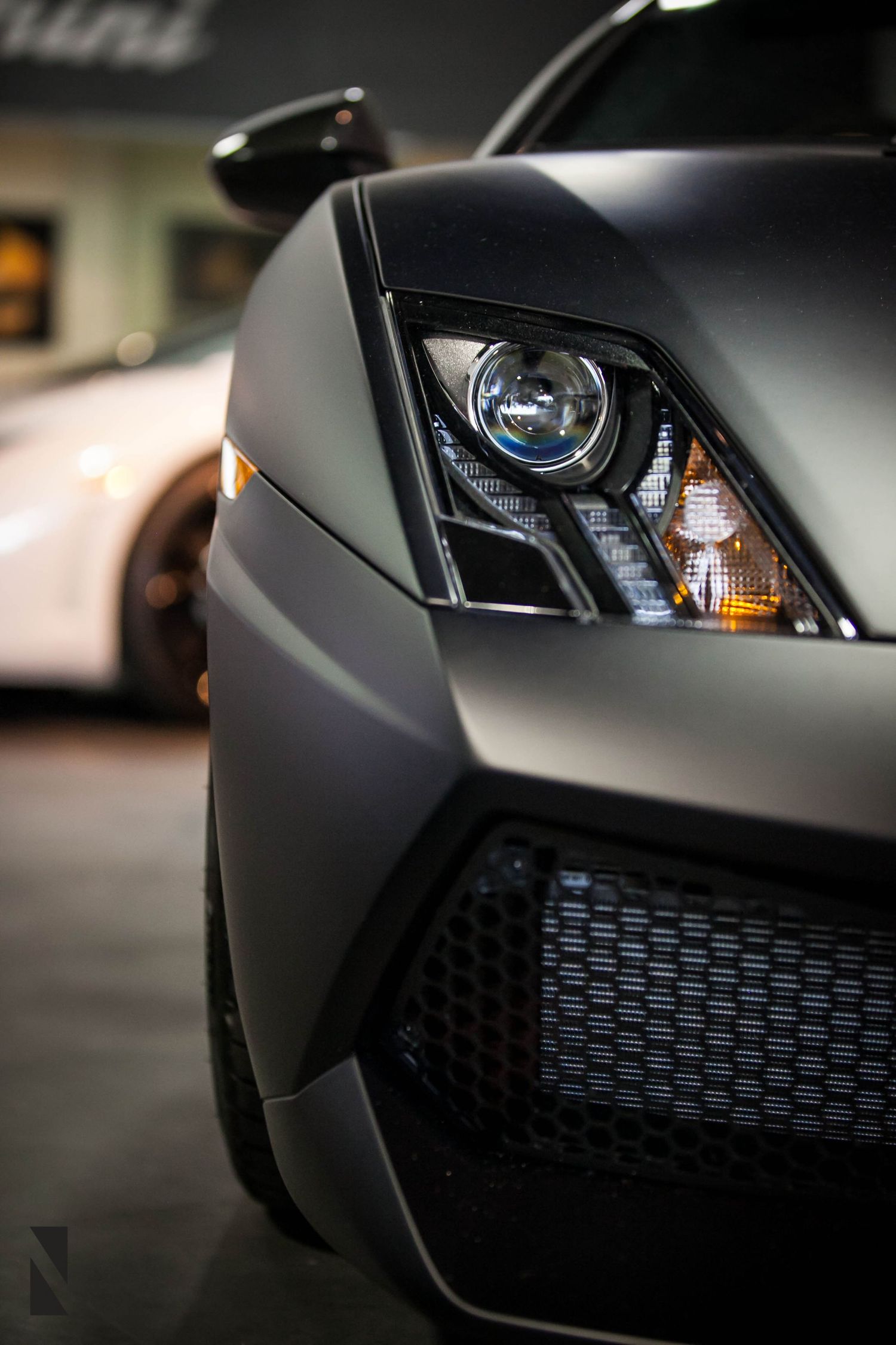 Close-up view of a matte black Lamborghini headlight and front grille showing aggressive modern design details.