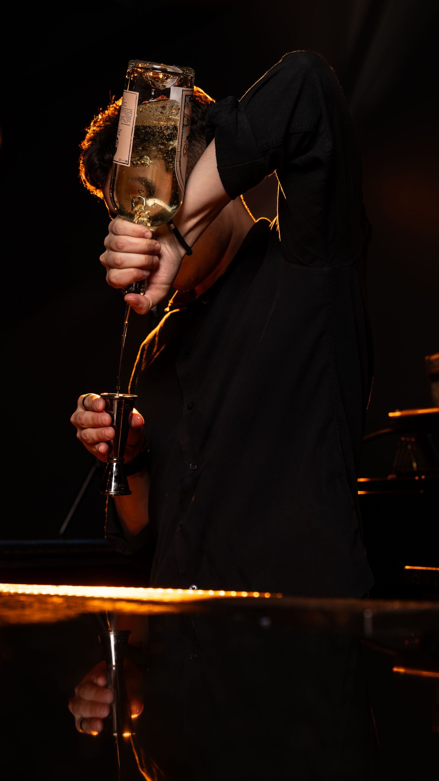 A performer in a black hoodie holds a bright lantern on stage during a moody theatrical performance.