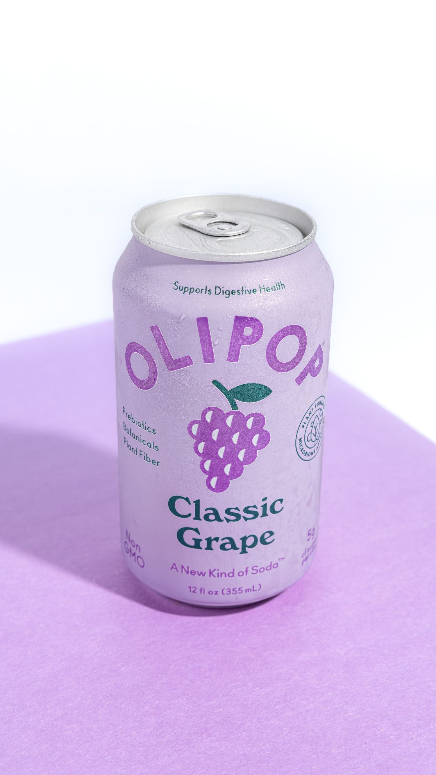 Four white aluminum cans with grape branding on a purple surface shown in a minimalist product photography style.
