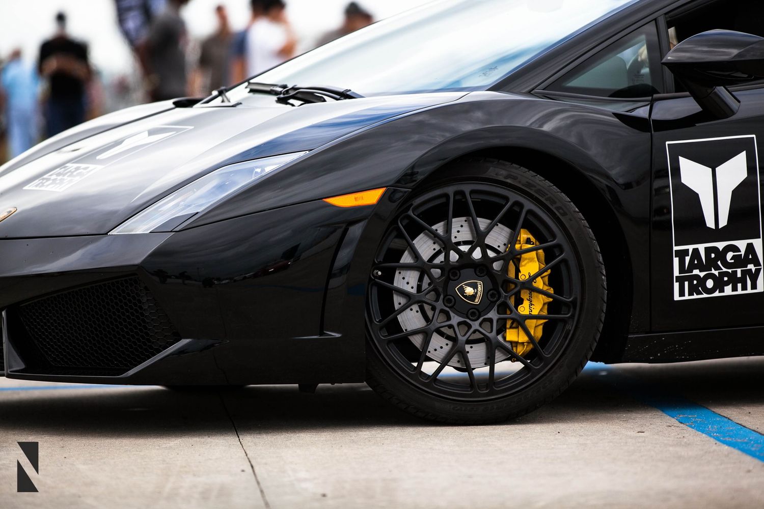 Black Lamborghini sports car with custom wheels and yellow brake calipers.