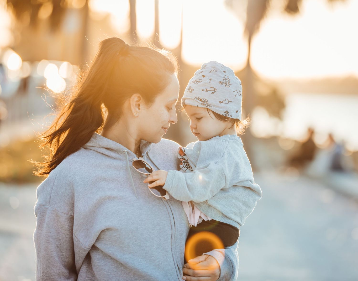 A tender sunset moment between parent and child on a warm evening with golden bokeh light in background.