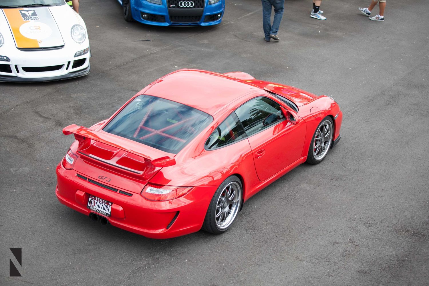 Bright red Porsche 911 GT3 with large rear spoiler viewed from above at a car meet.