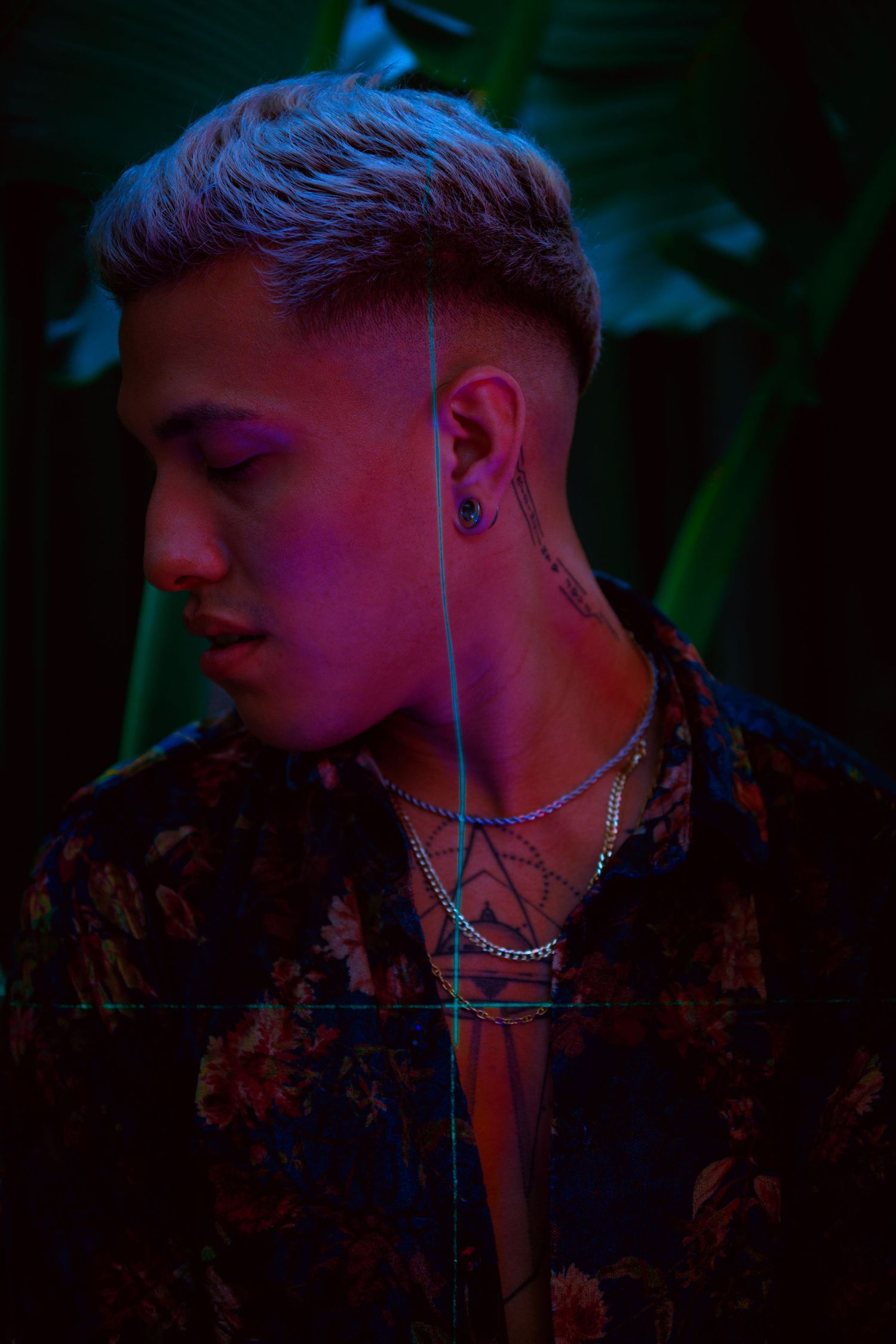 Side profile portrait with floral jacket in dark lighting with neon accents.