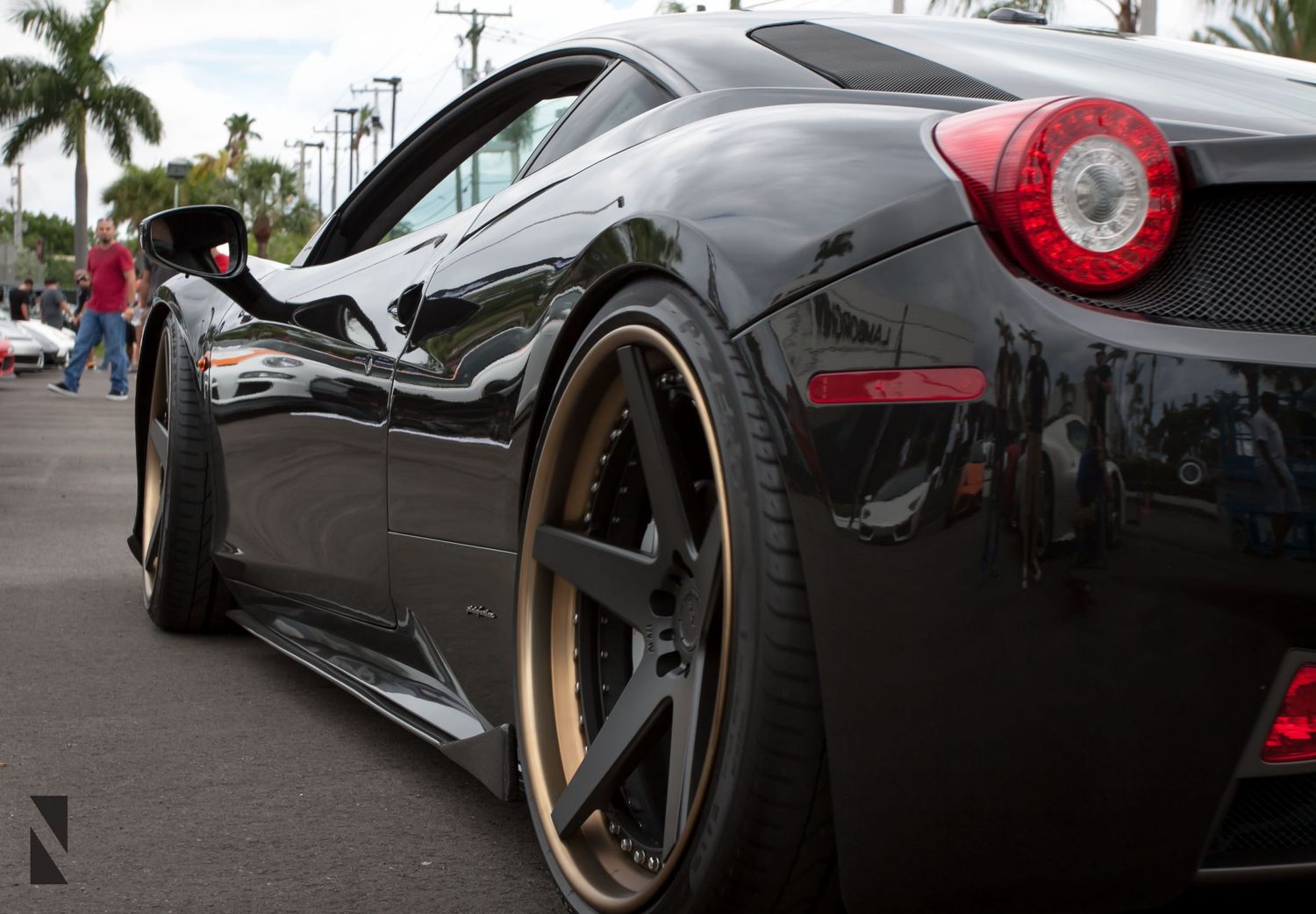 Black Ferrari 458 Italia supercar with custom gold wheels parked on street showcasing aggressive side profile design.