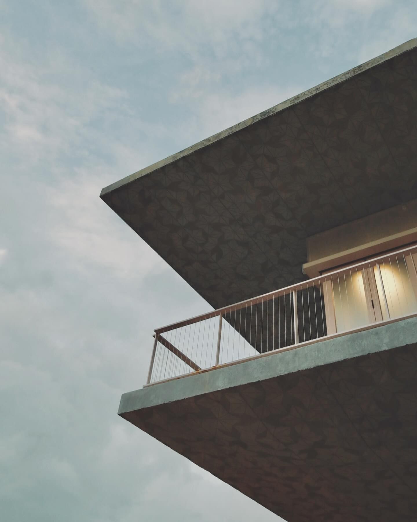 Modern building balcony jutting out against cloudy sky at dusk.