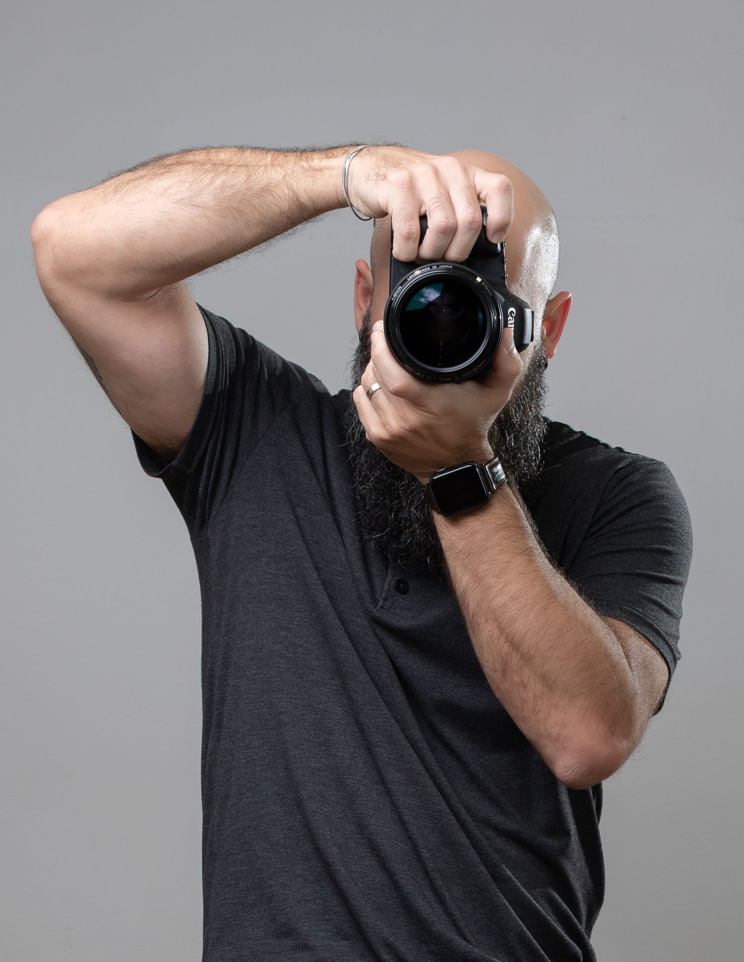 Photographer holding professional camera against grey background.