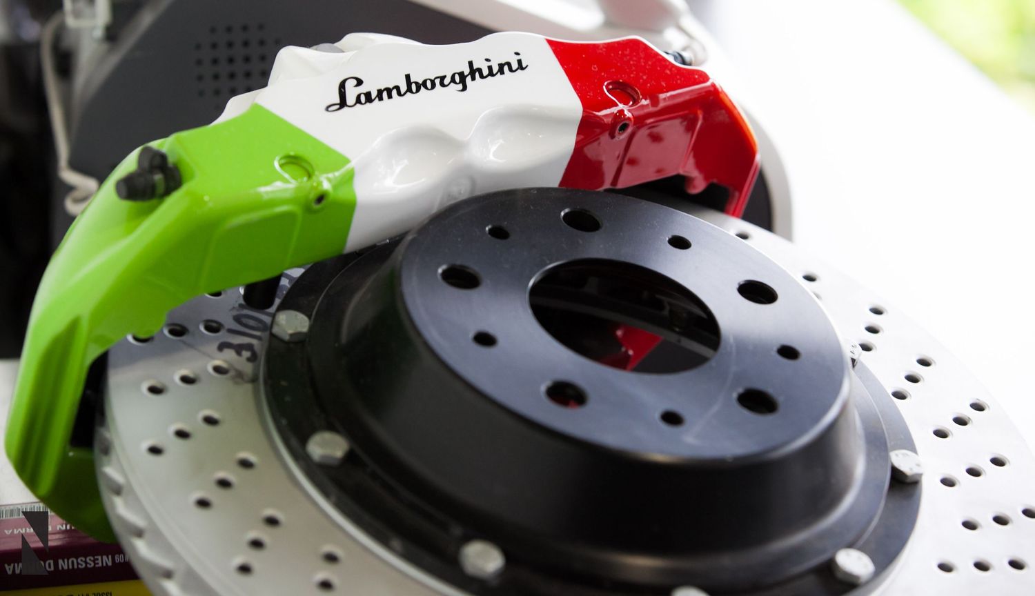 Close-up of a Lamborghini performance brake disc and caliper painted in Italian flag colors of red, white and green.