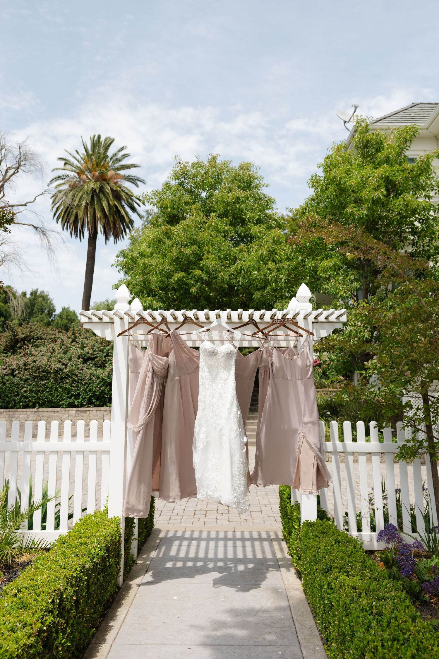 Outdoor garden path with white picket fence and elegant beige curtains draped on a pergola creating a romantic entrance.