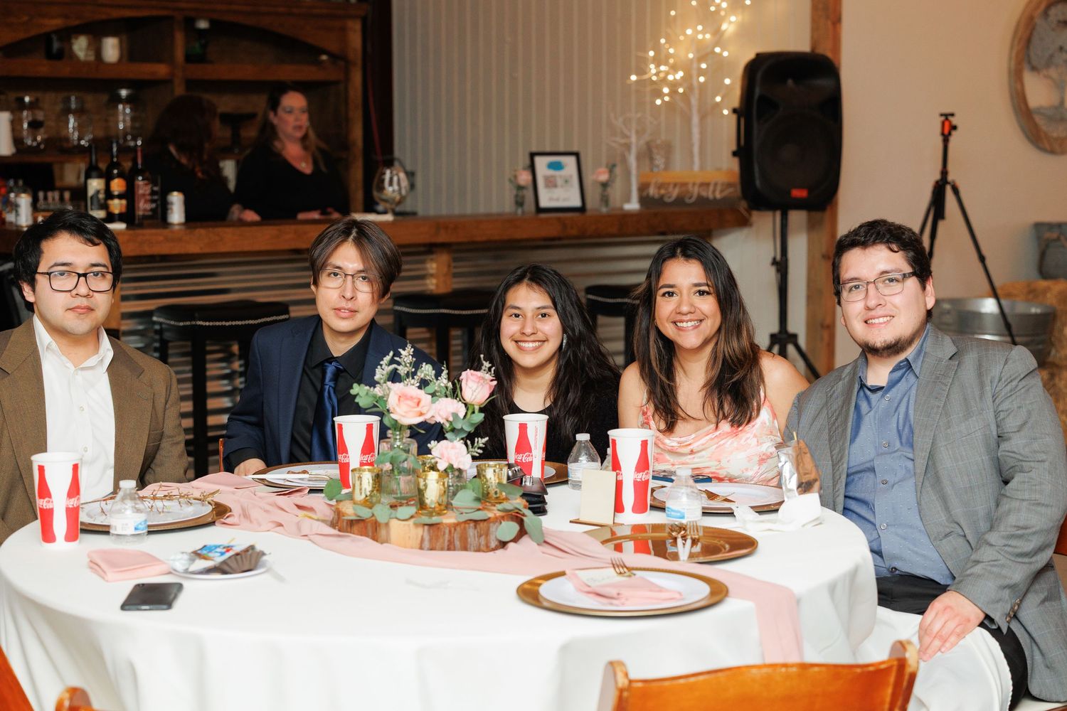 A group of people gathered around a long dining table with food and drinks during a holiday celebration.