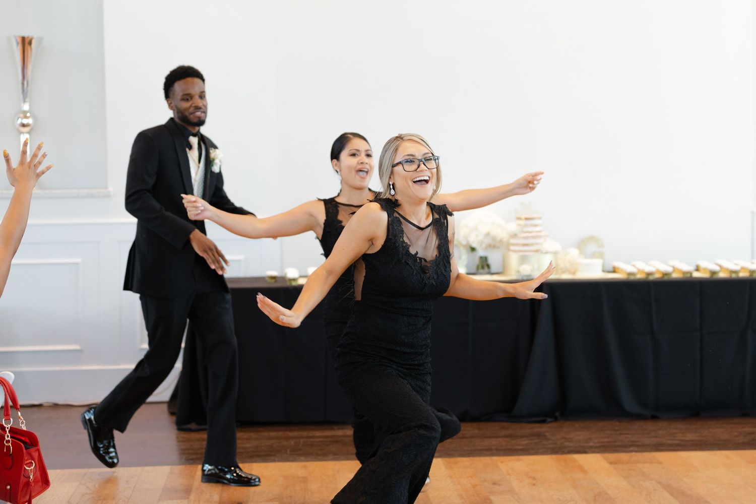 Dancers in black outfits perform a synchronized dance routine in a bright studio space.