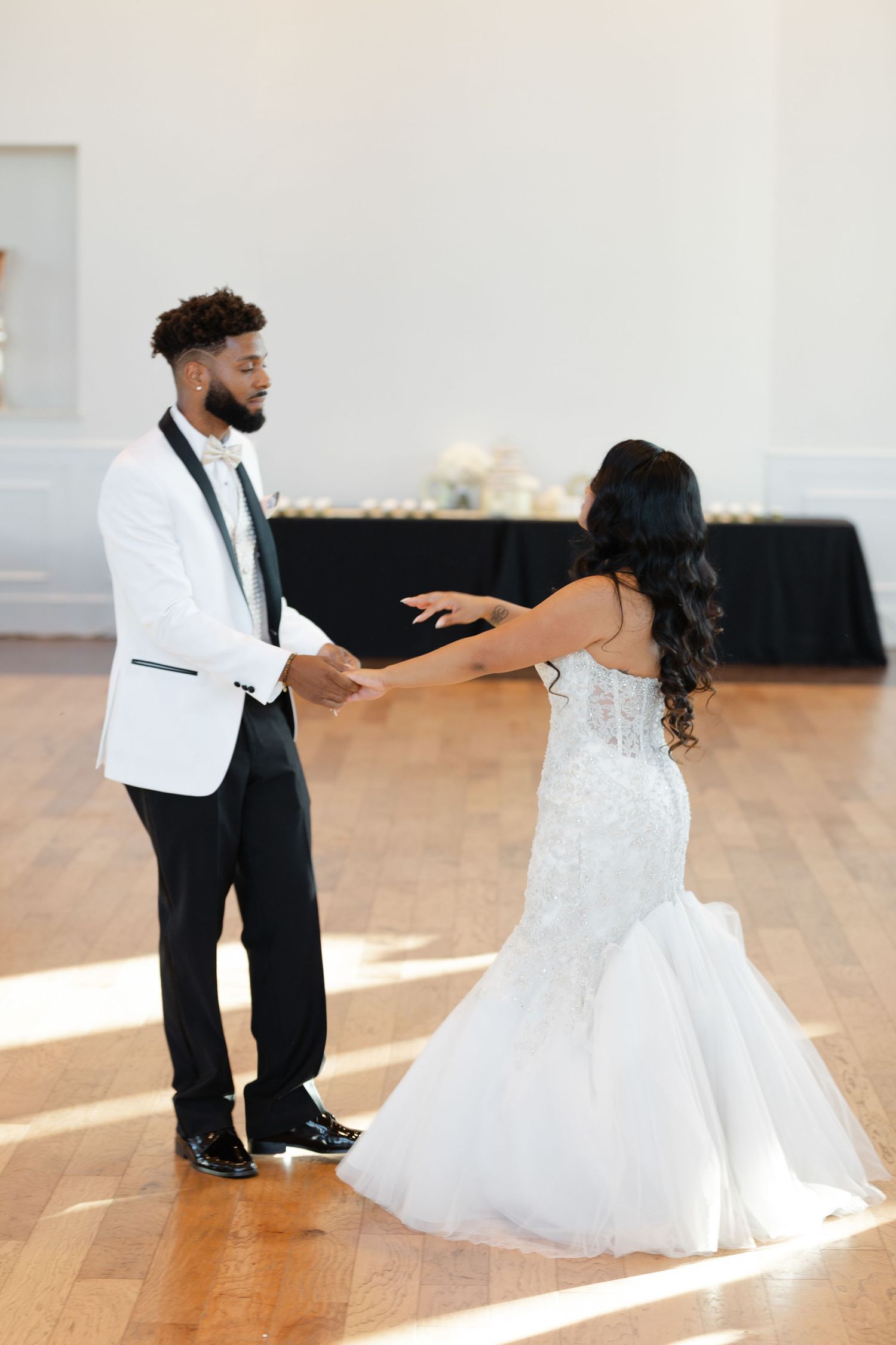 A series of dance moves between a couple in wedding attire on a wooden dance floor.