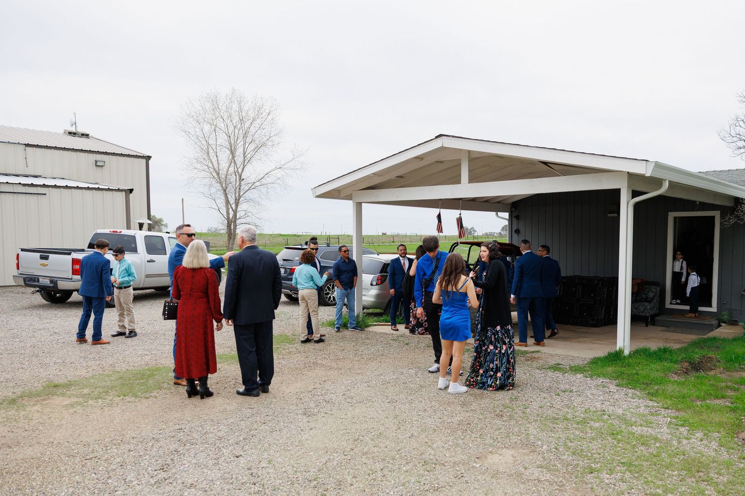 People walk between buildings at a rural facility on an overcast day.