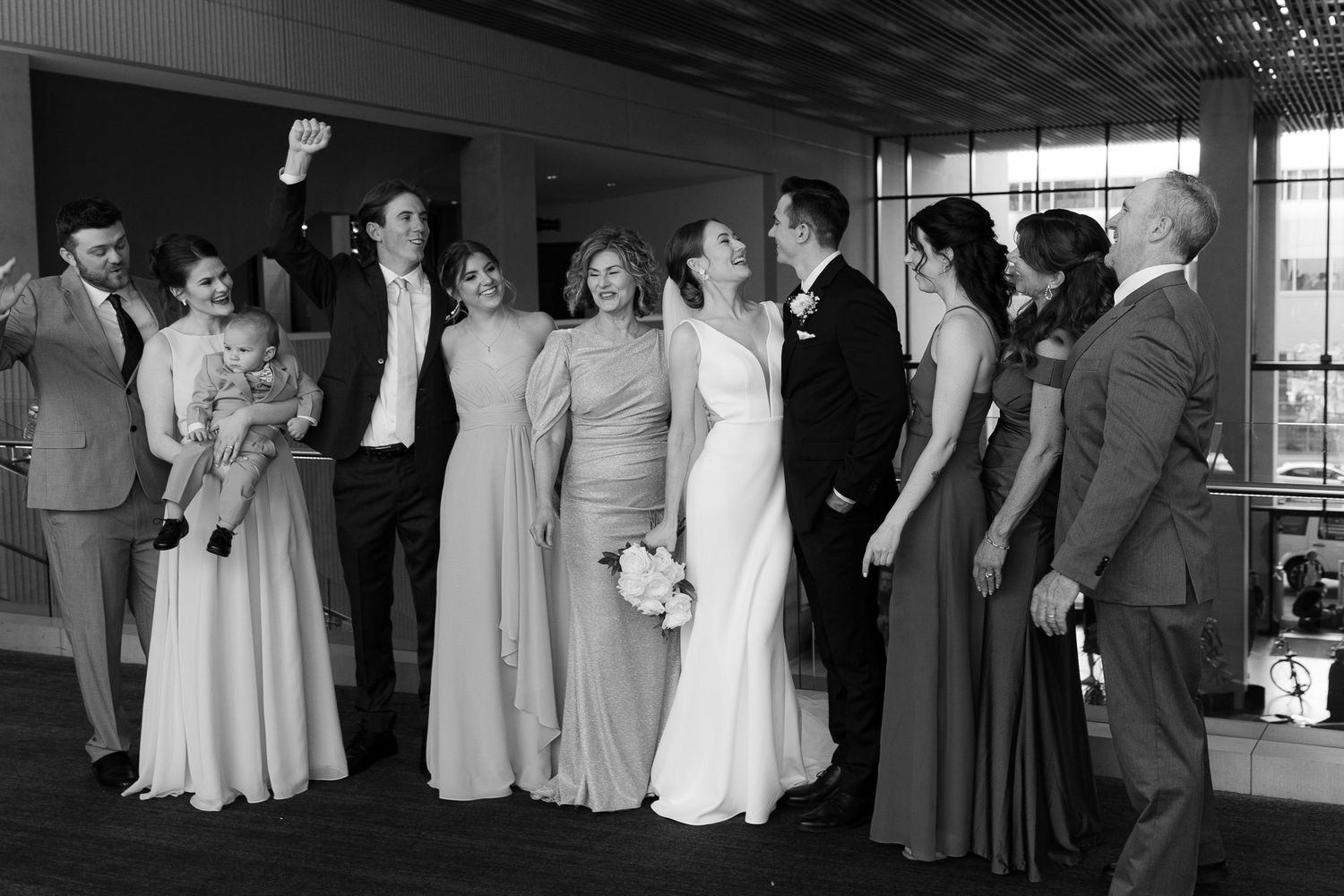 A wedding party stands together in formal attire at an elegant indoor venue during a celebration.