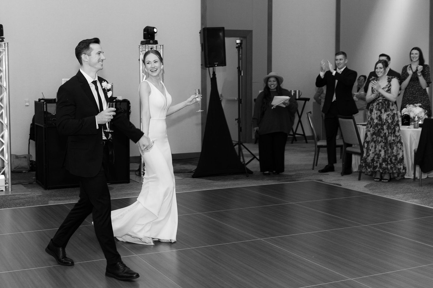 A couple performs an elegant dance move during their first dance at a wedding reception with guests watching.