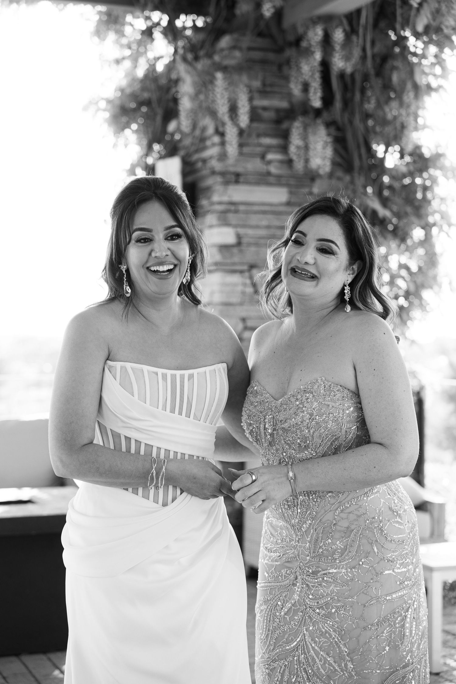 Two people in formal attire share joyful laughter during what appears to be a wedding celebration.