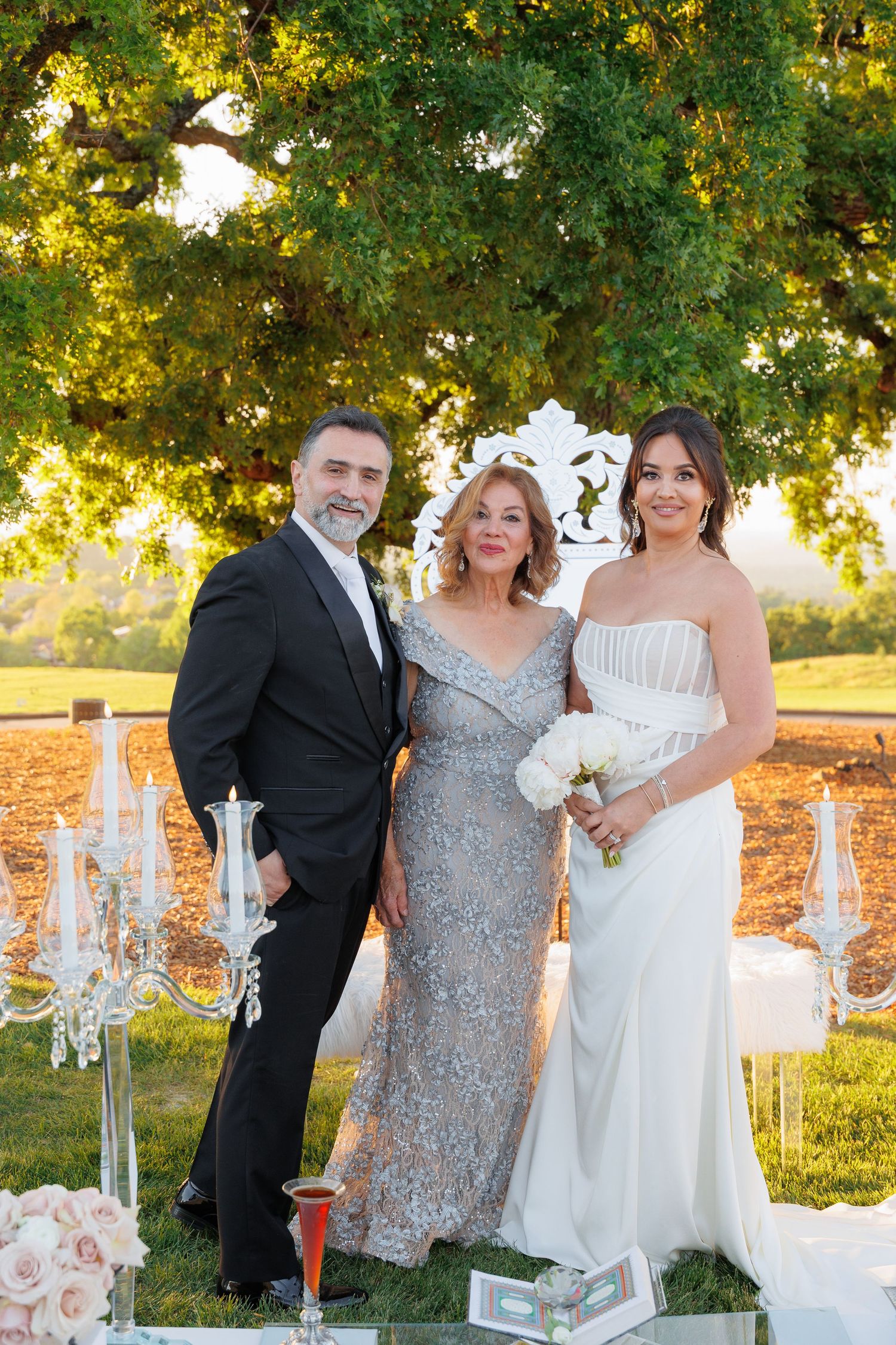 Outdoor wedding celebration with decorative crystal candelabras and floral arrangements at sunset.