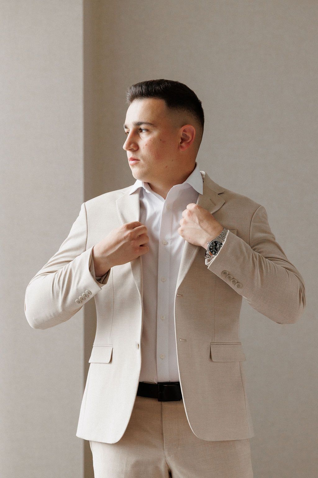 Multiple shots of someone wearing a cream colored blazer and white shirt against a neutral wall background.