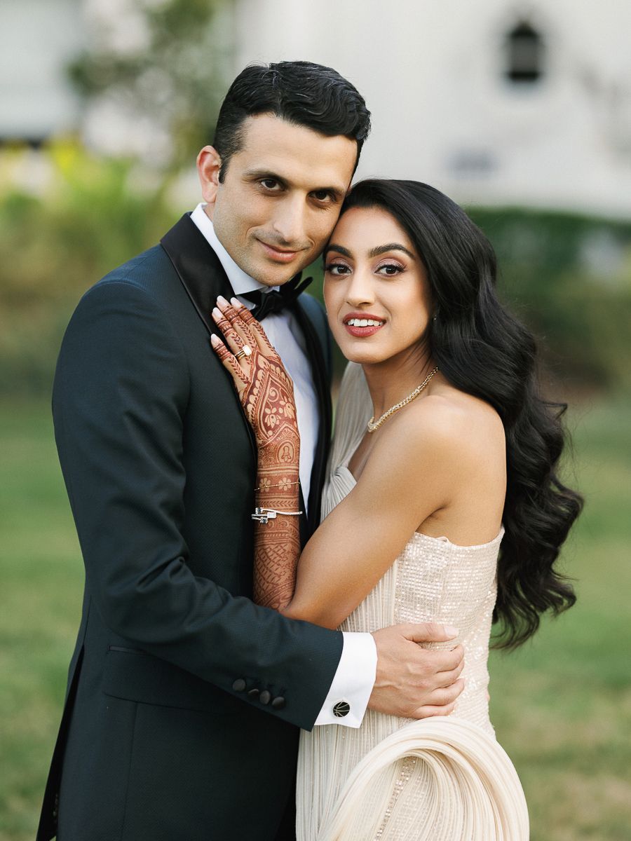 A romantic outdoor wedding photoshoot with a couple in formal attire embracing and smiling.