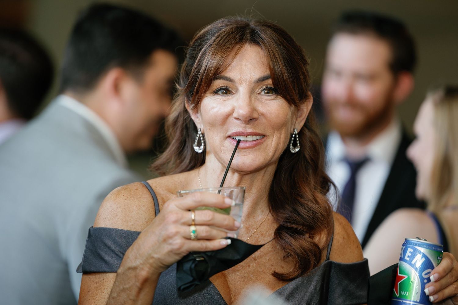 A person smiles and laughs while enjoying a social gathering at an elegant event.