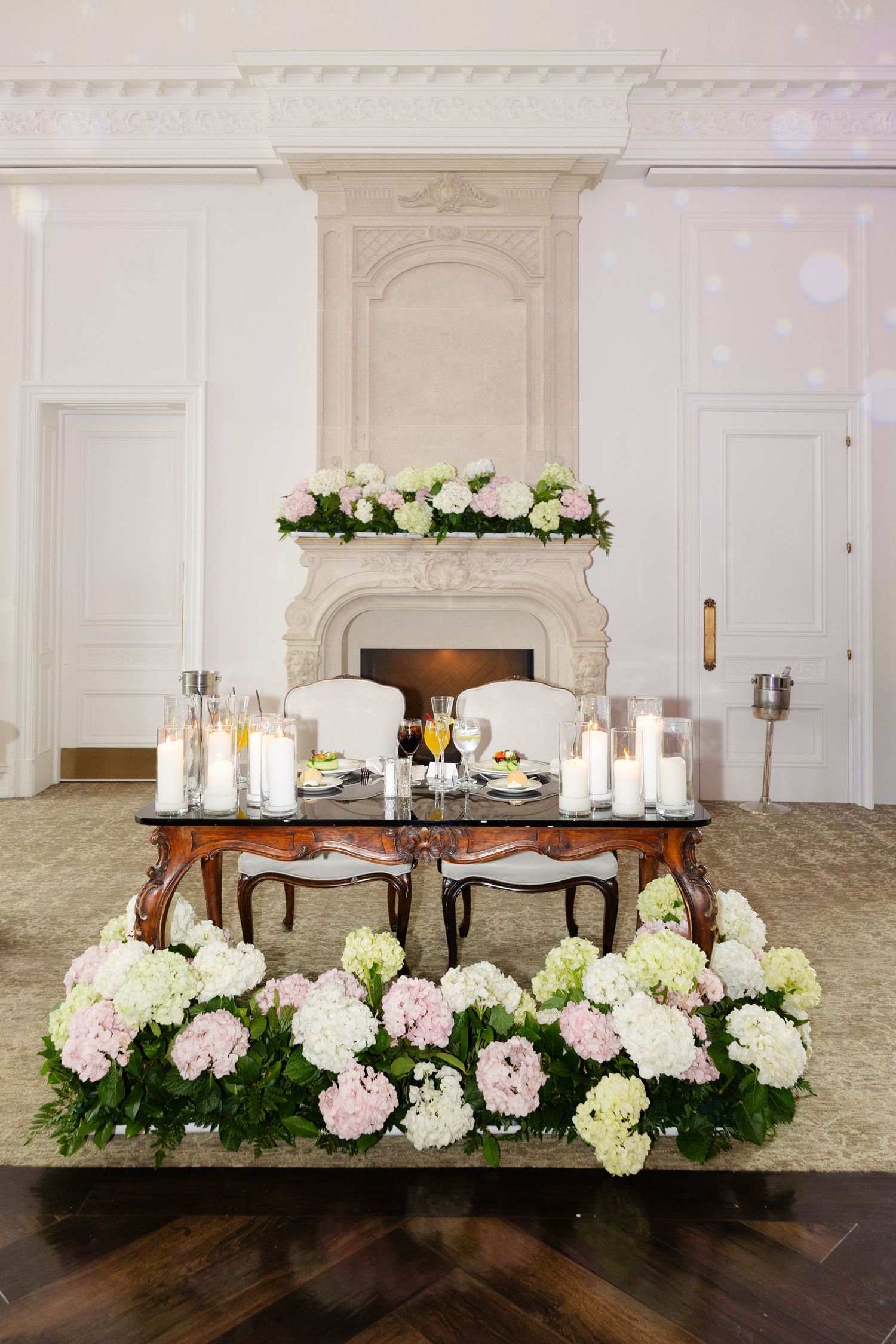 Elegant wedding reception table setup with white candles and pink and white hydrangea floral arrangements.