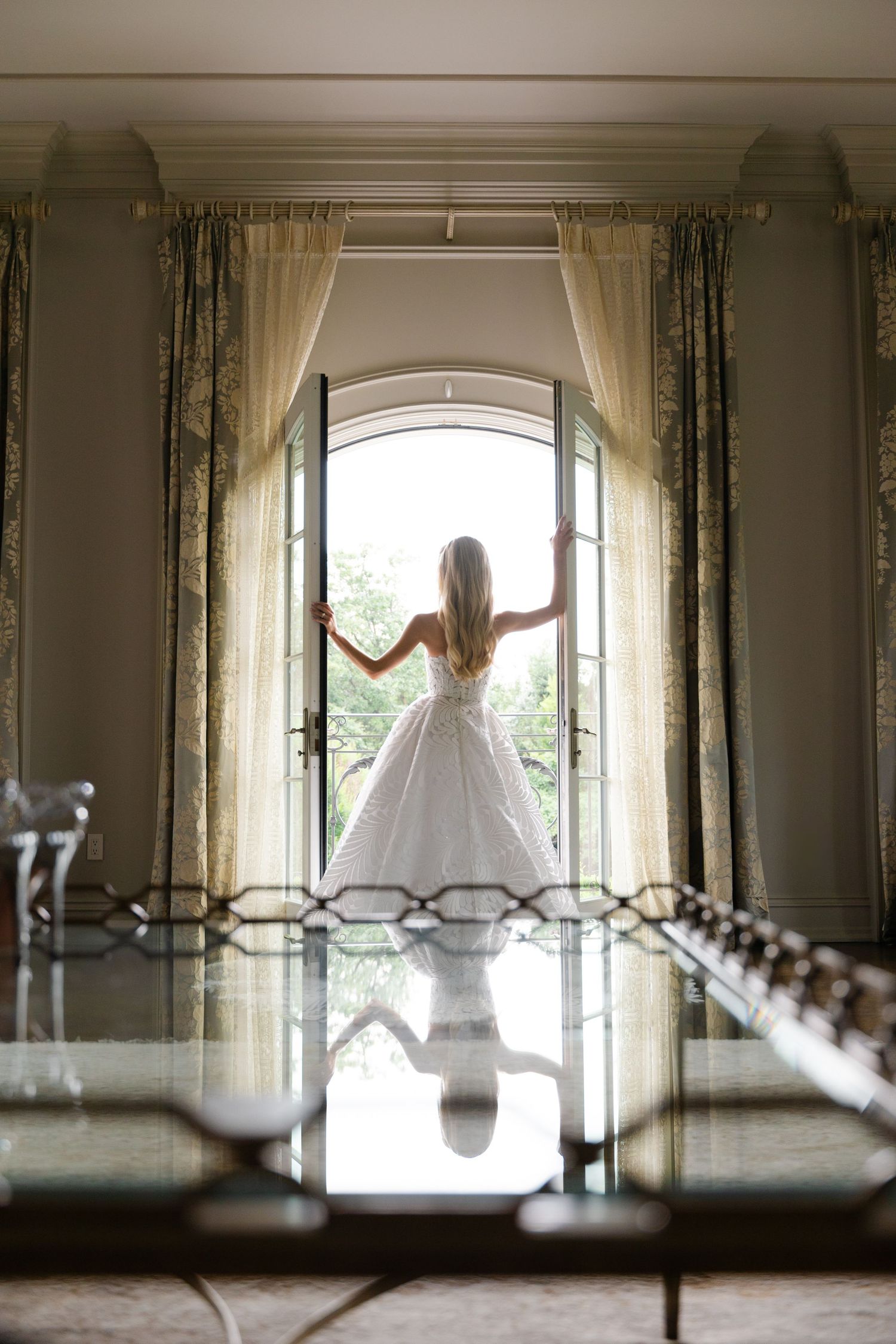A series of four artistic silhouette photos showing a bride in a flowing white gown posing against bright arched windows.