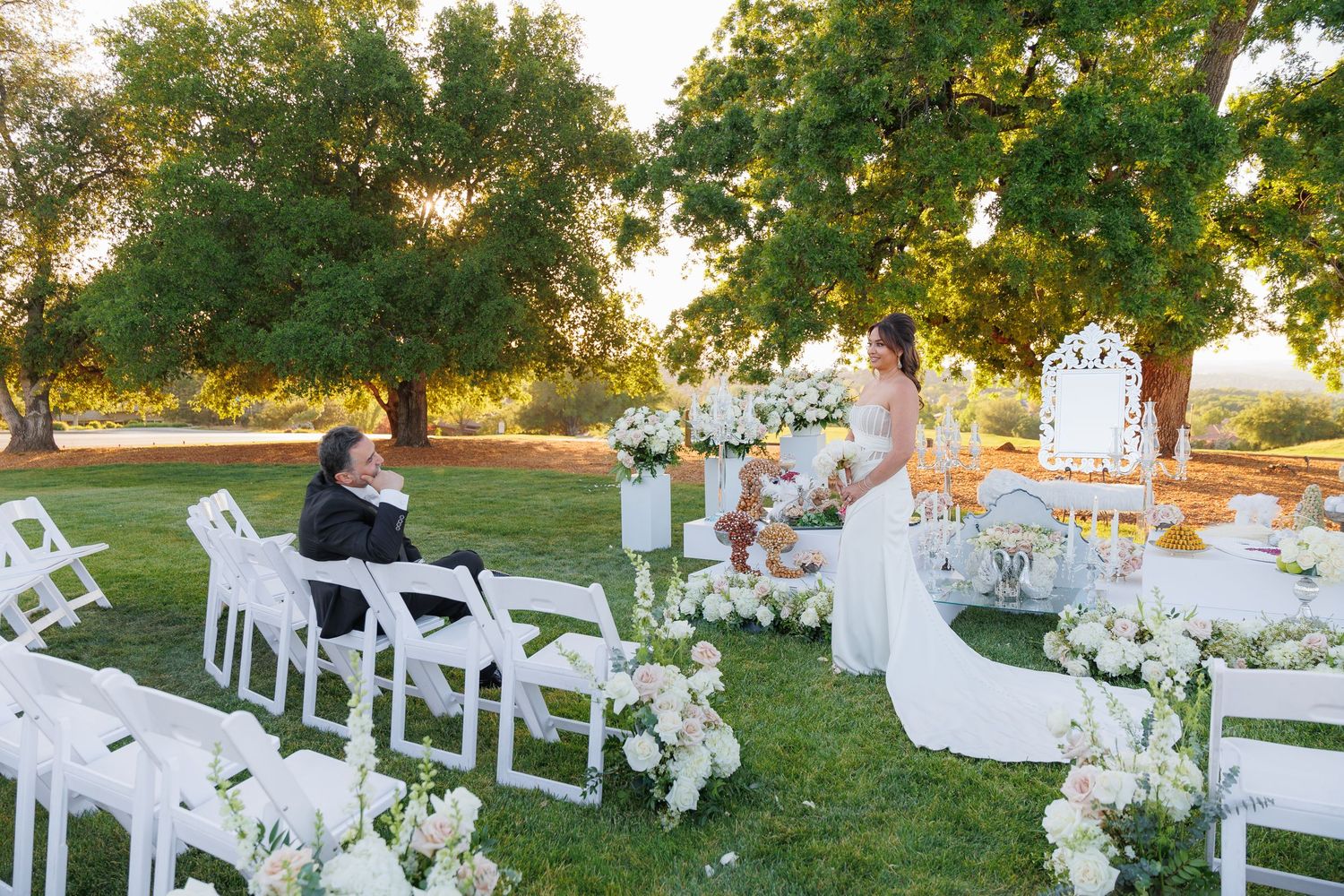White folding chairs arranged in rows on a grassy lawn for an outdoor wedding ceremony at sunset.