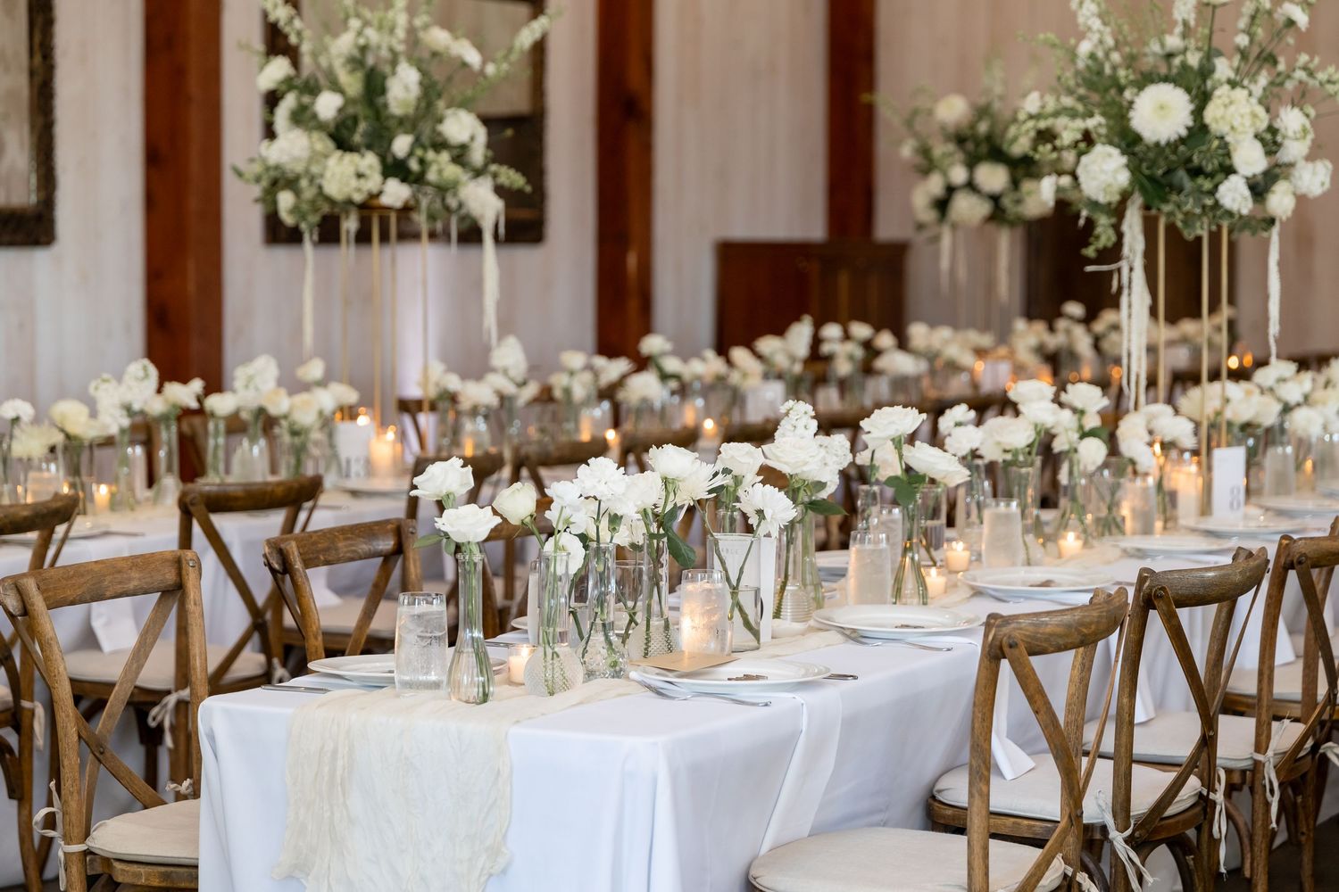 Elegant wedding reception tables decorated with white flowers and greenery in a refined indoor setting.