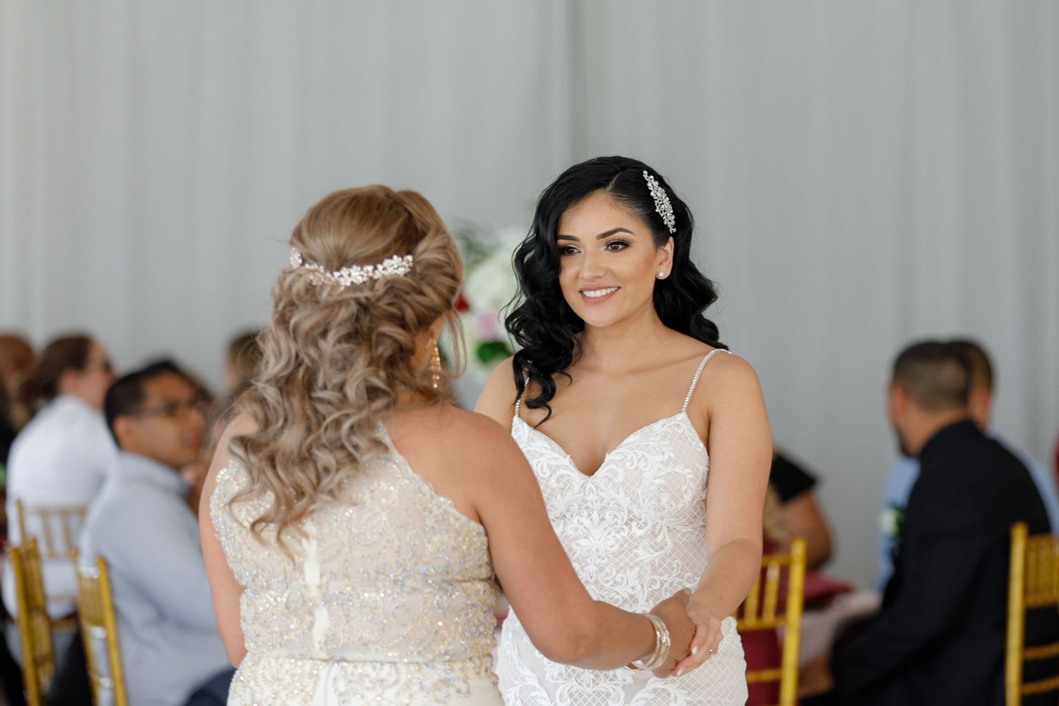 A bride and groom share their first dance at an elegant wedding reception with guests watching in the background.