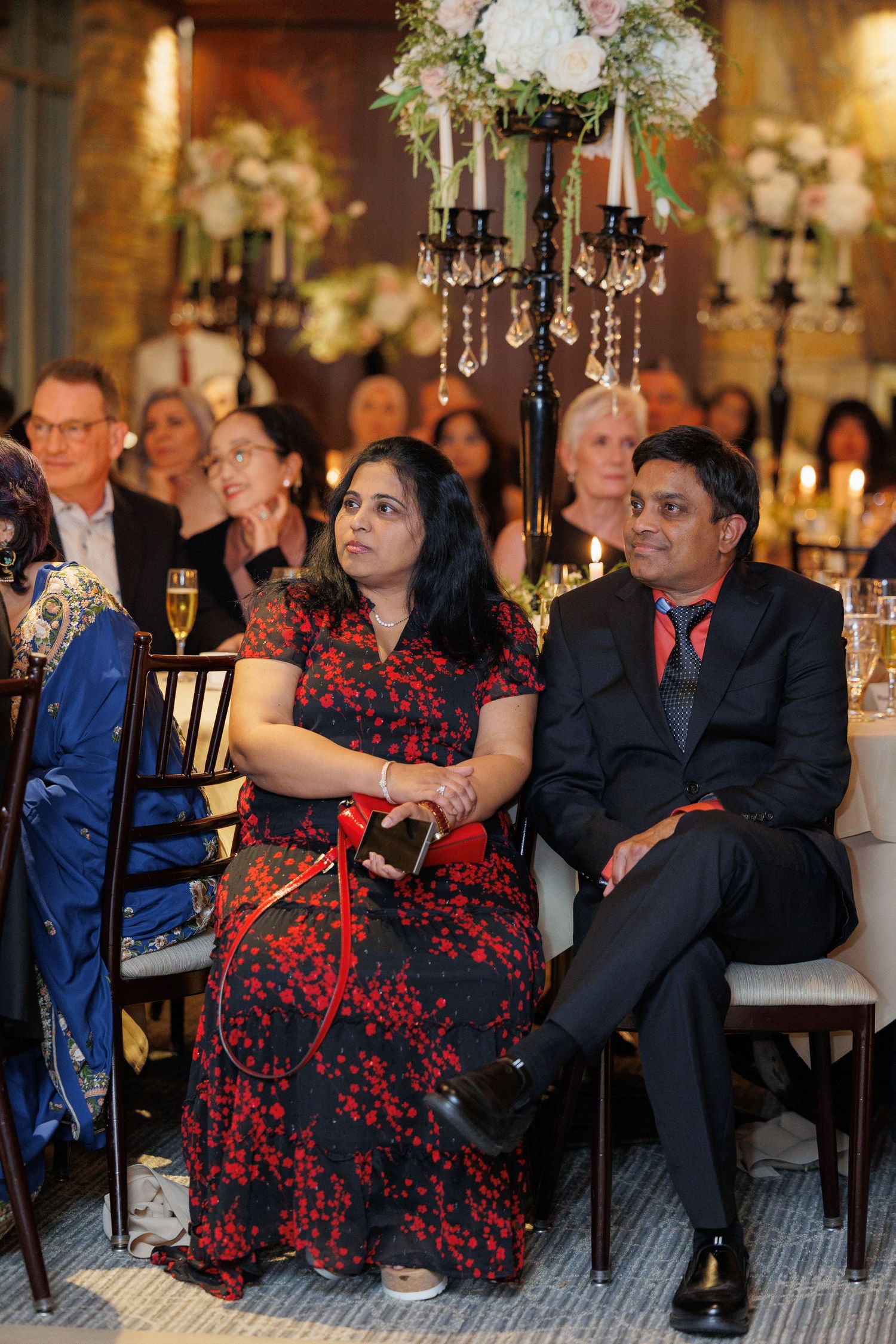 Couple in formal attire sharing a romantic dance moment at an elegant candlelit reception venue.