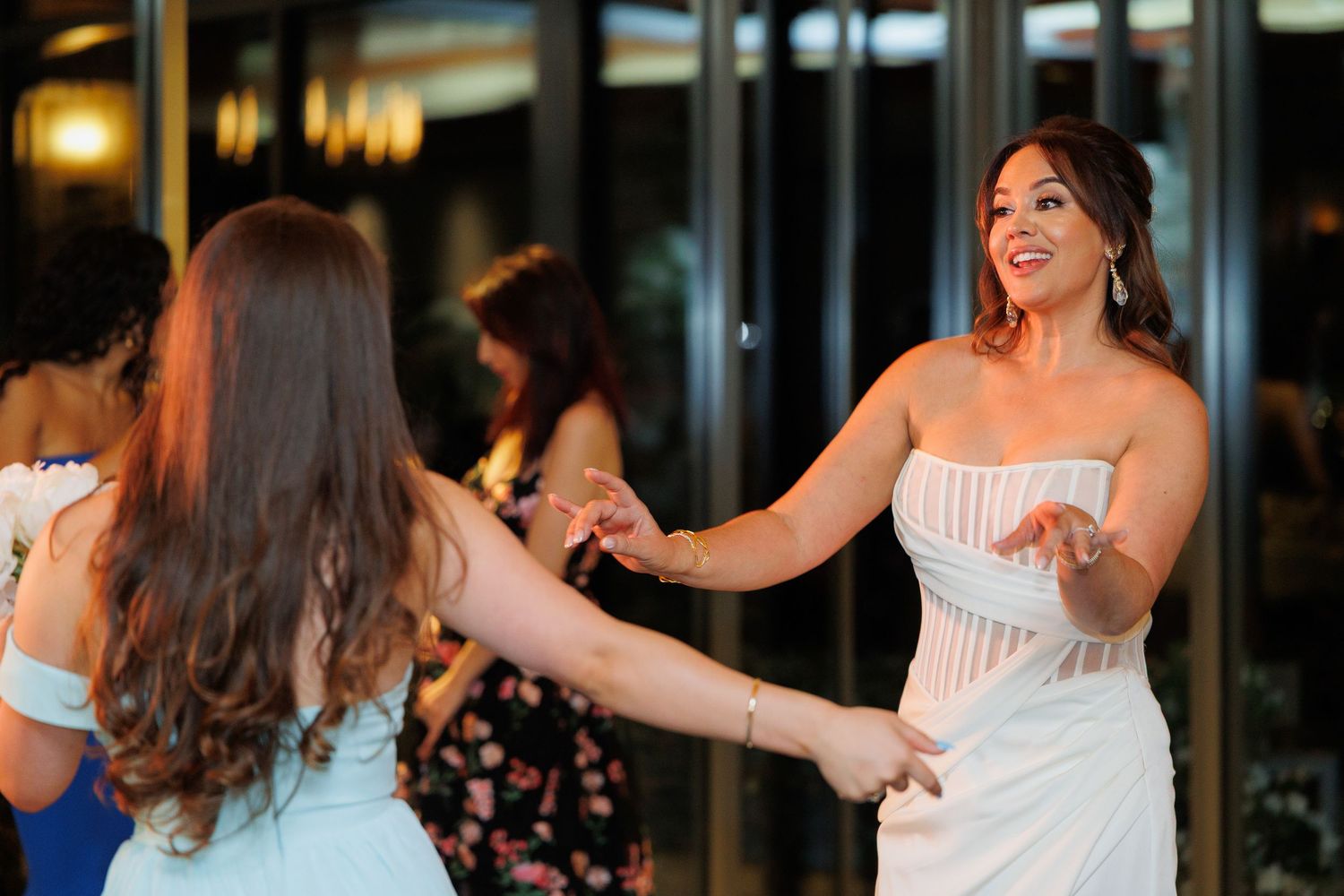 A group of people dancing and celebrating at a wedding reception in an elegant indoor venue.